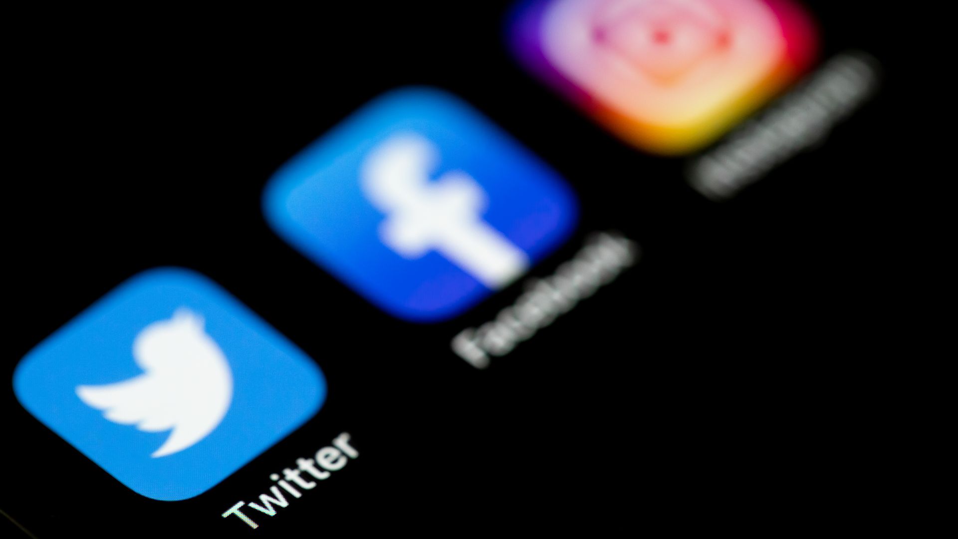 The Twitter, Facebook and Instagram logos on the screen of an iPhone.