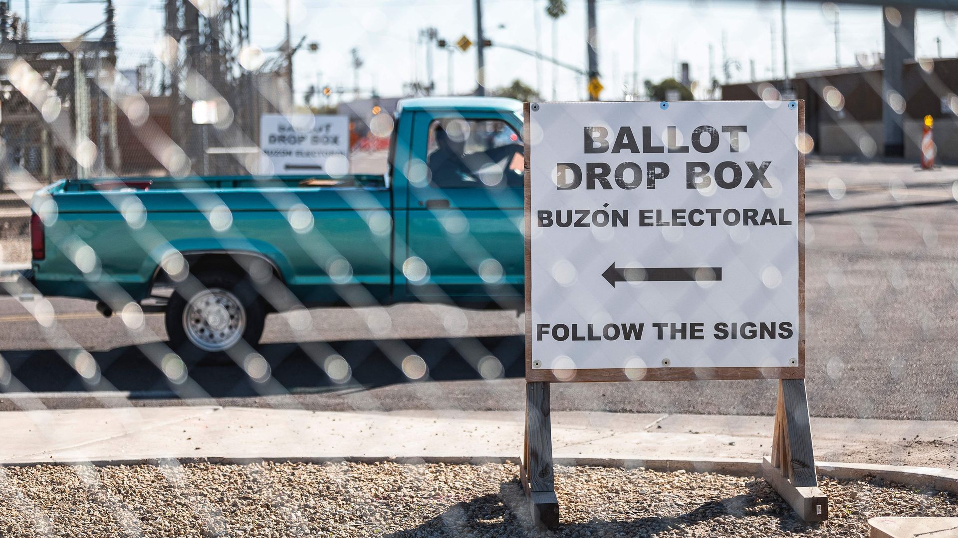 Photo of a sign indicating the location of the ballot drop box behind a fence