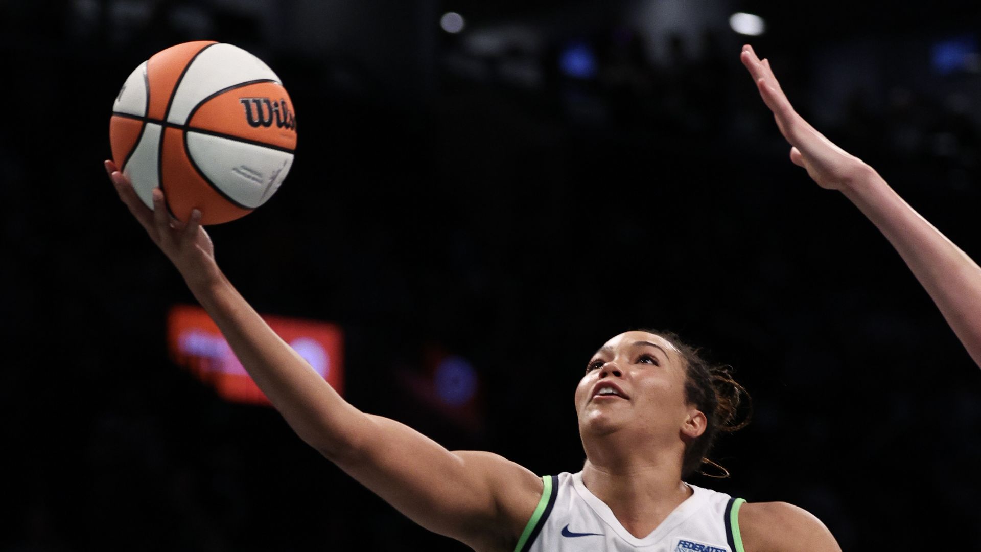 A basketball player stretches up to grab a basketball in midair