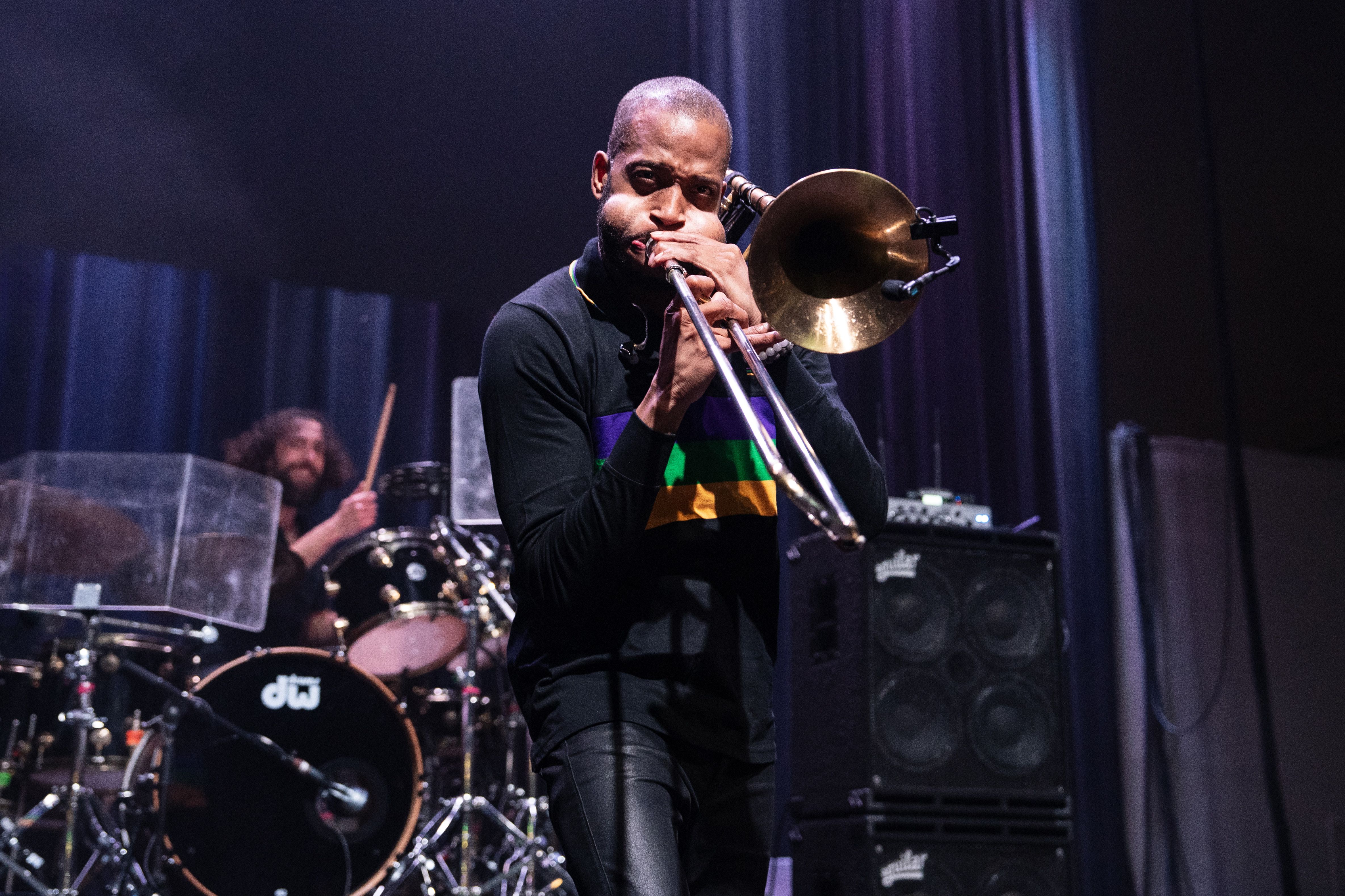 Photo shows Trombone Shorty playing a trombone on stage.