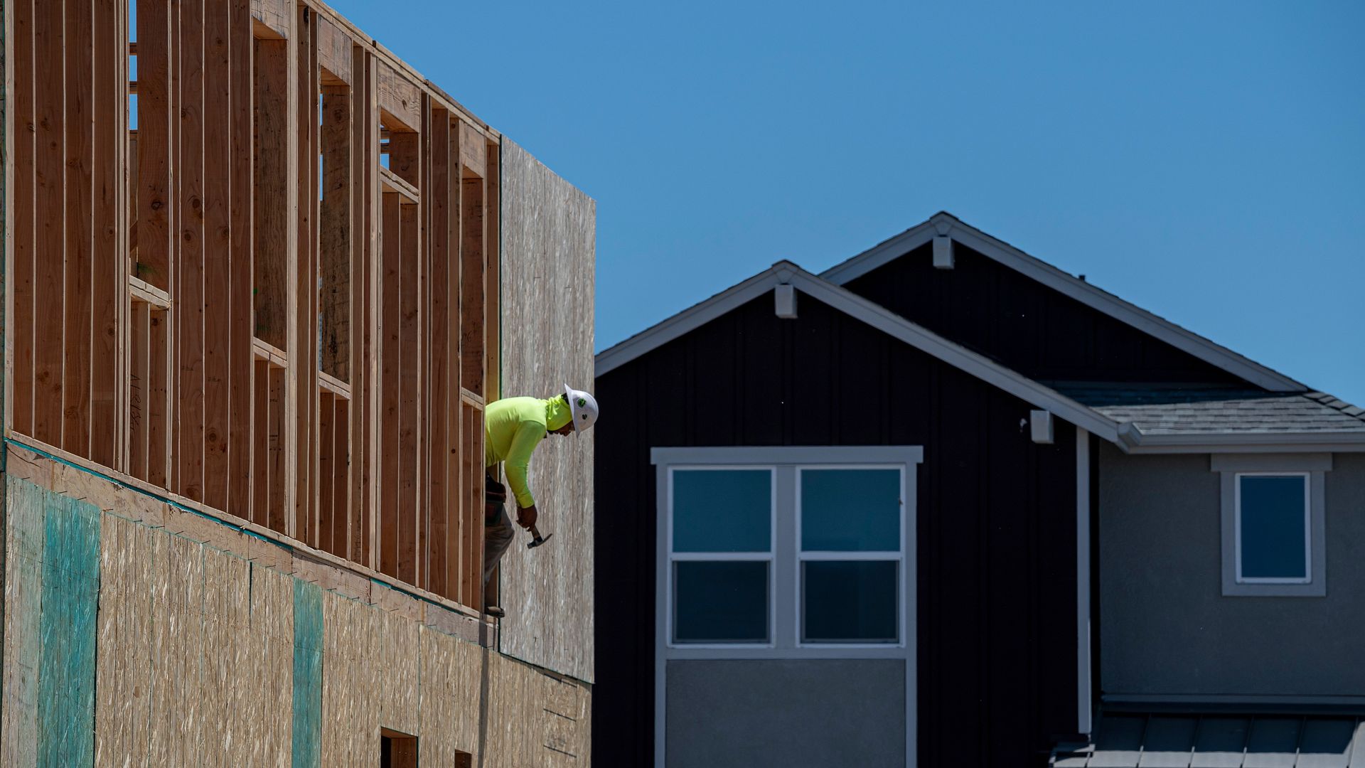 A construction worker helps install framing on a house