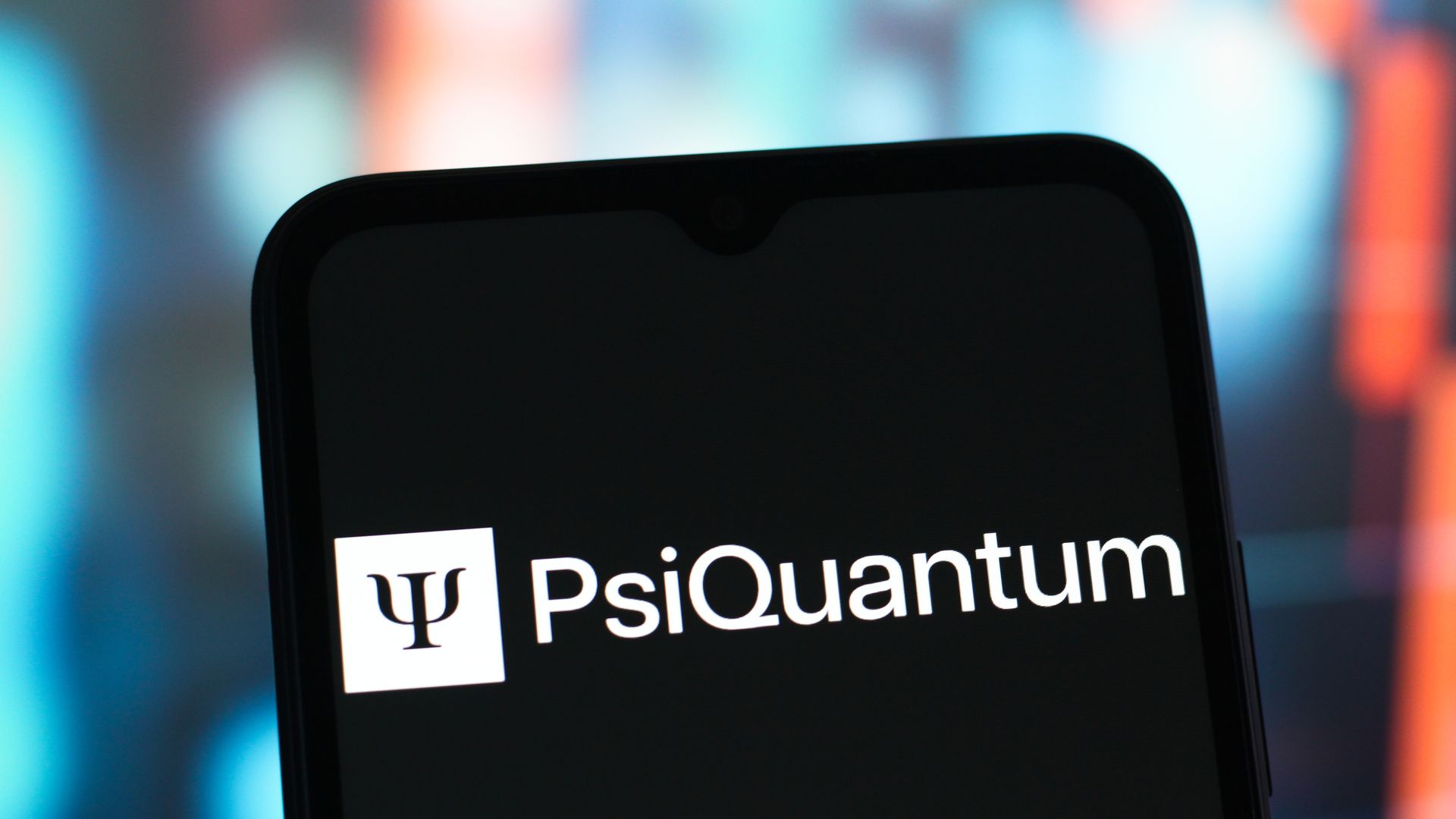 Smartphone screen displaying the white PsiQuantum logo and text on a black background with a blurred colorful background.