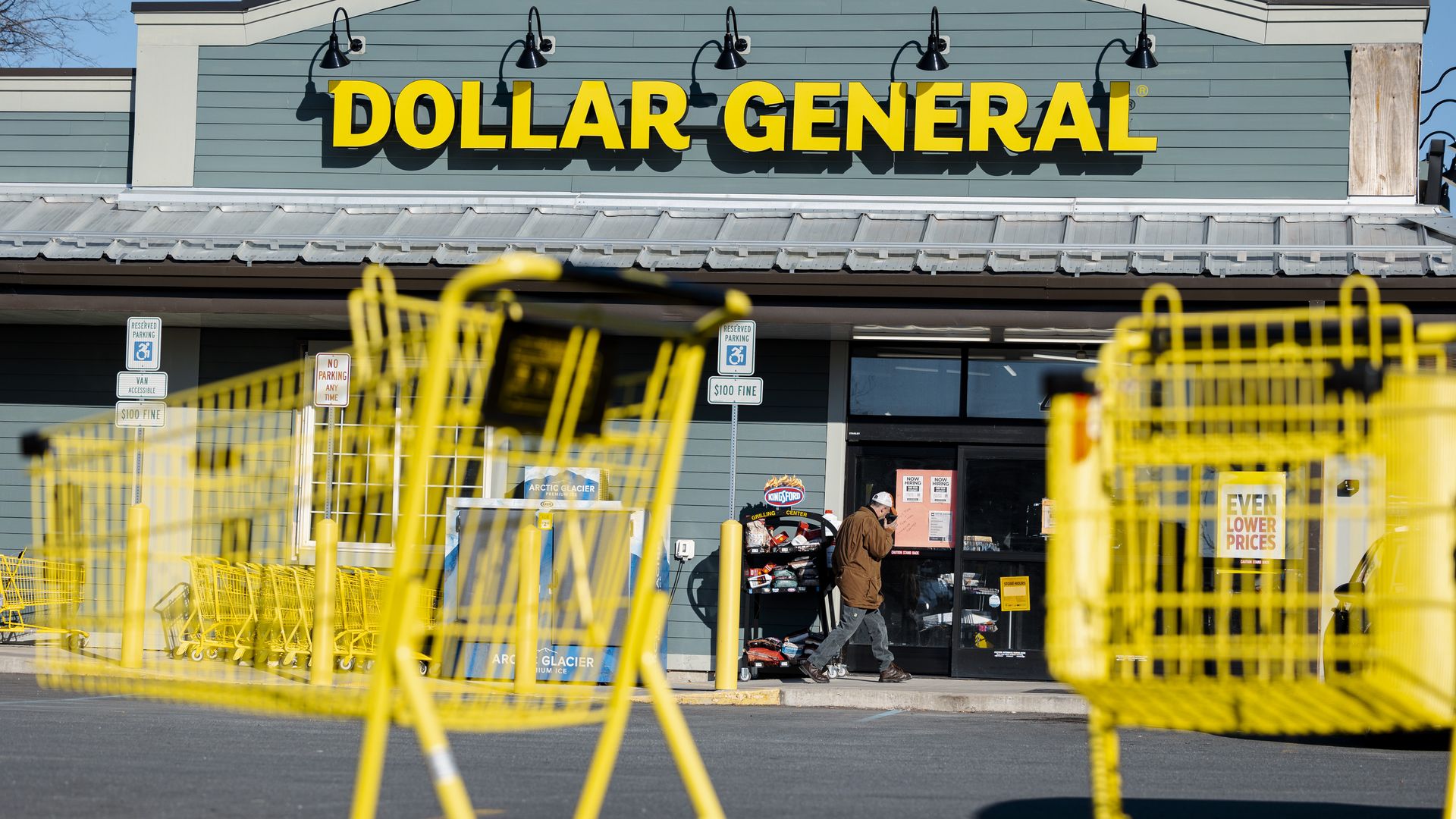 Two yellow grocery cards are out of focus in the foreground of a photo of a Dollar General in focus in the background.