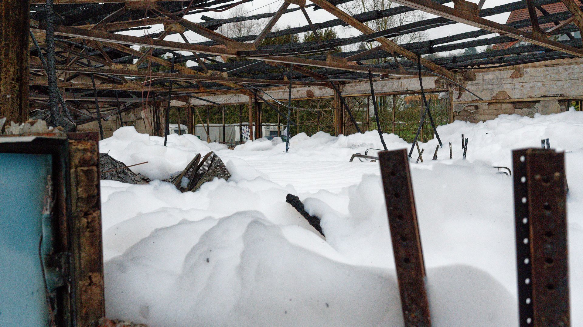 A photo of firefighting foam across the ground of a burned building.