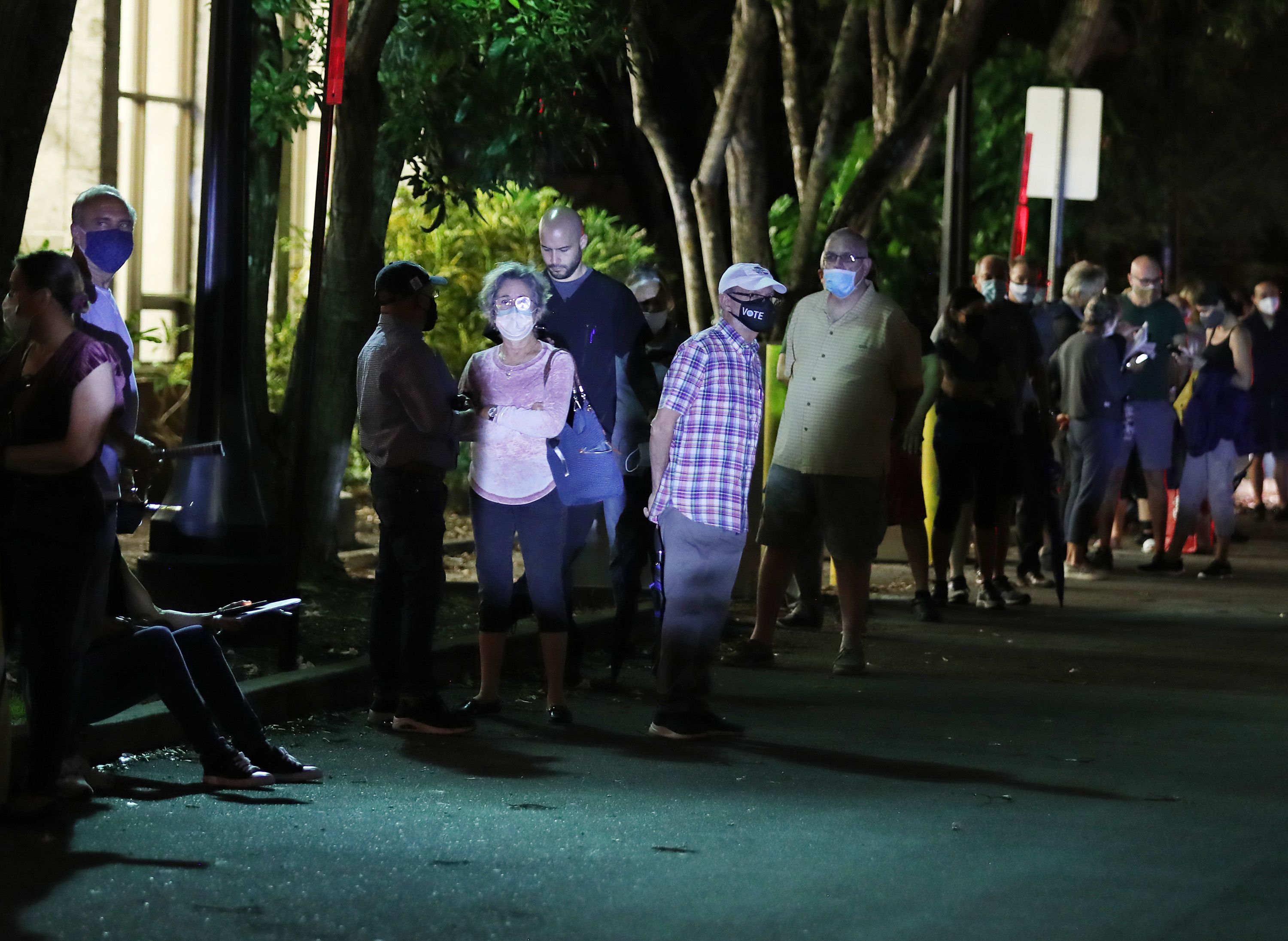 Voters stand outside in a line at night 