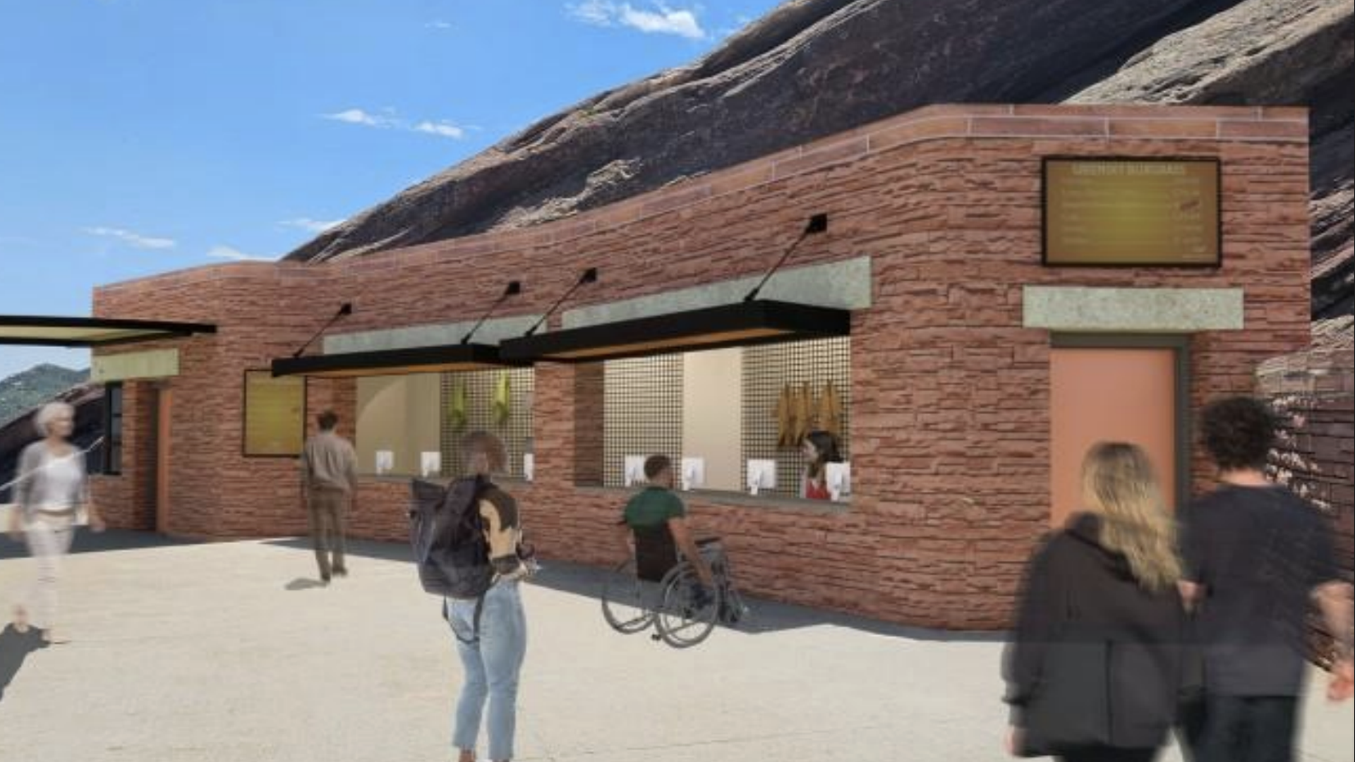 Outdoor brick concession stand with black awnings, people including one in a wheelchair, a rocky hill in the background, and a clear blue sky.