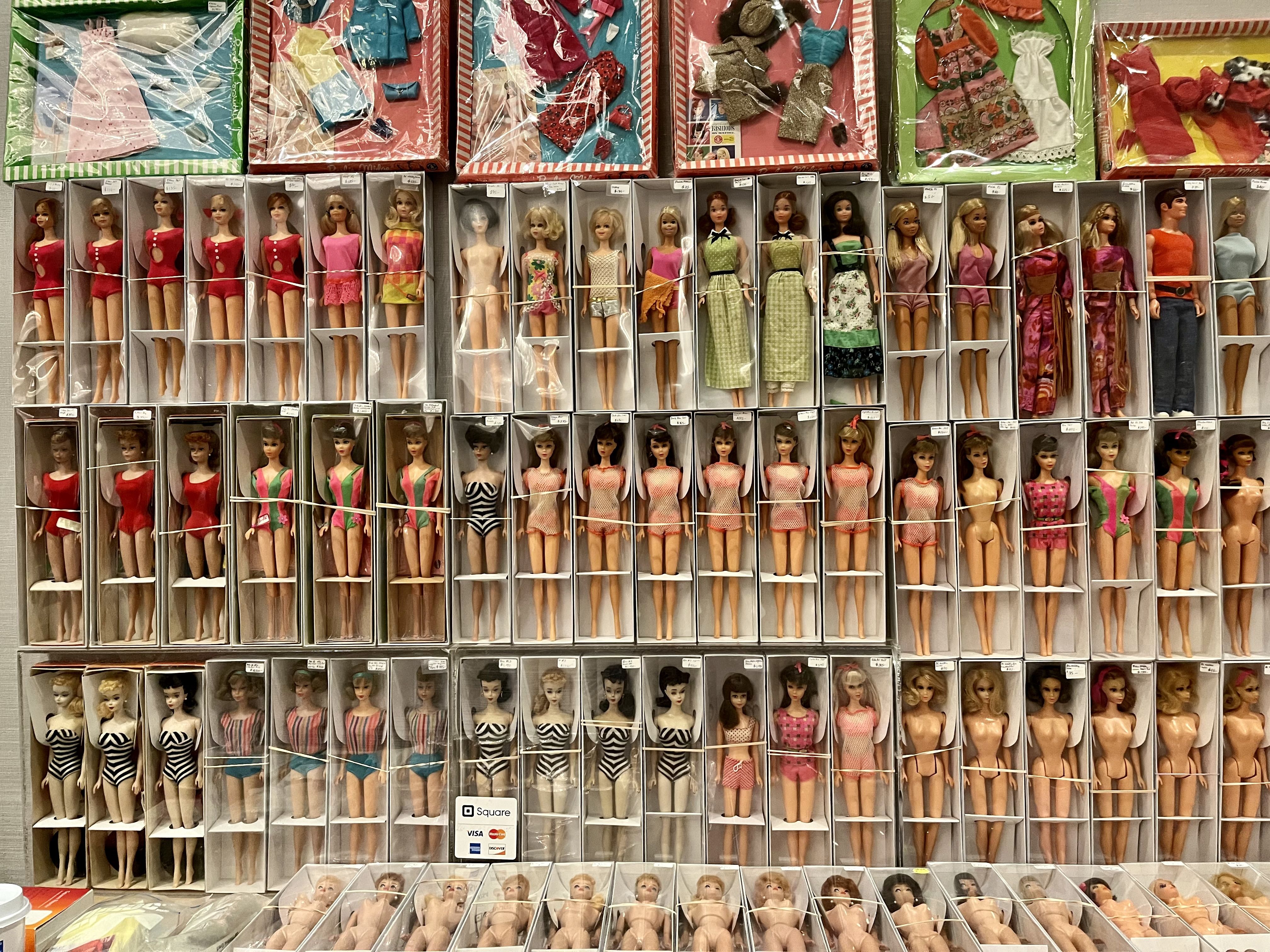 Several shelves of Barbie dolls in different-color clothing.