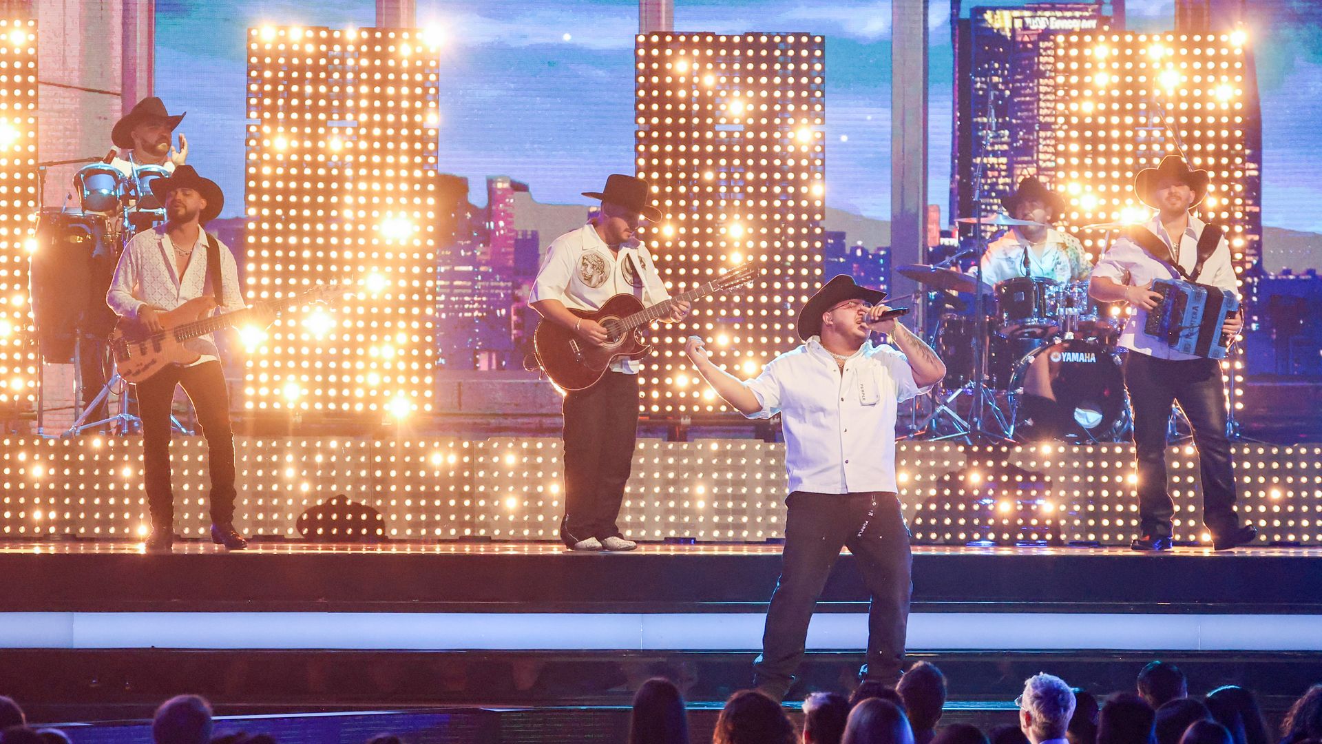 Men with guitars in cowboy hats perform on a stage