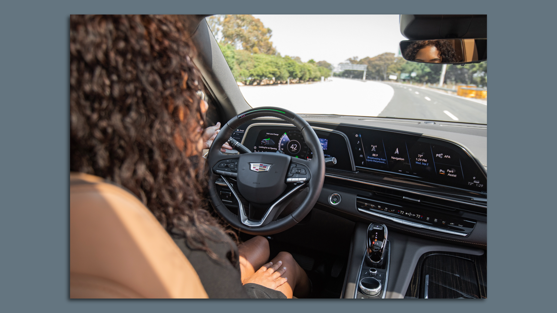 Image looking over the shoulder of a woman using Cadillac's hands-free SuperCruise technology. 