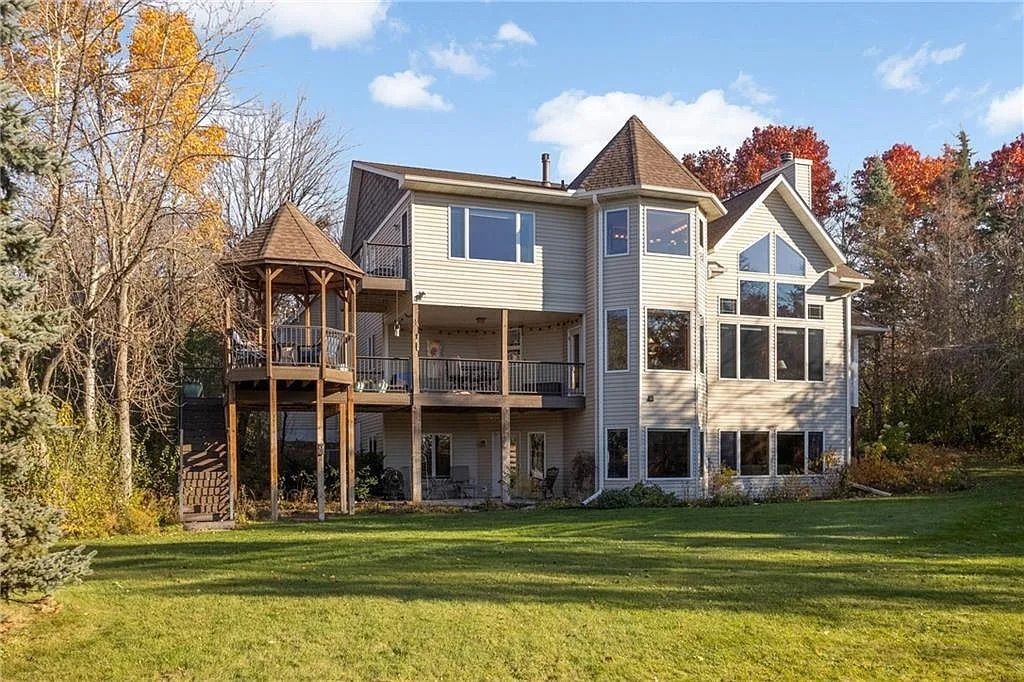 The back view of a three story house with a large porch and big windows. 