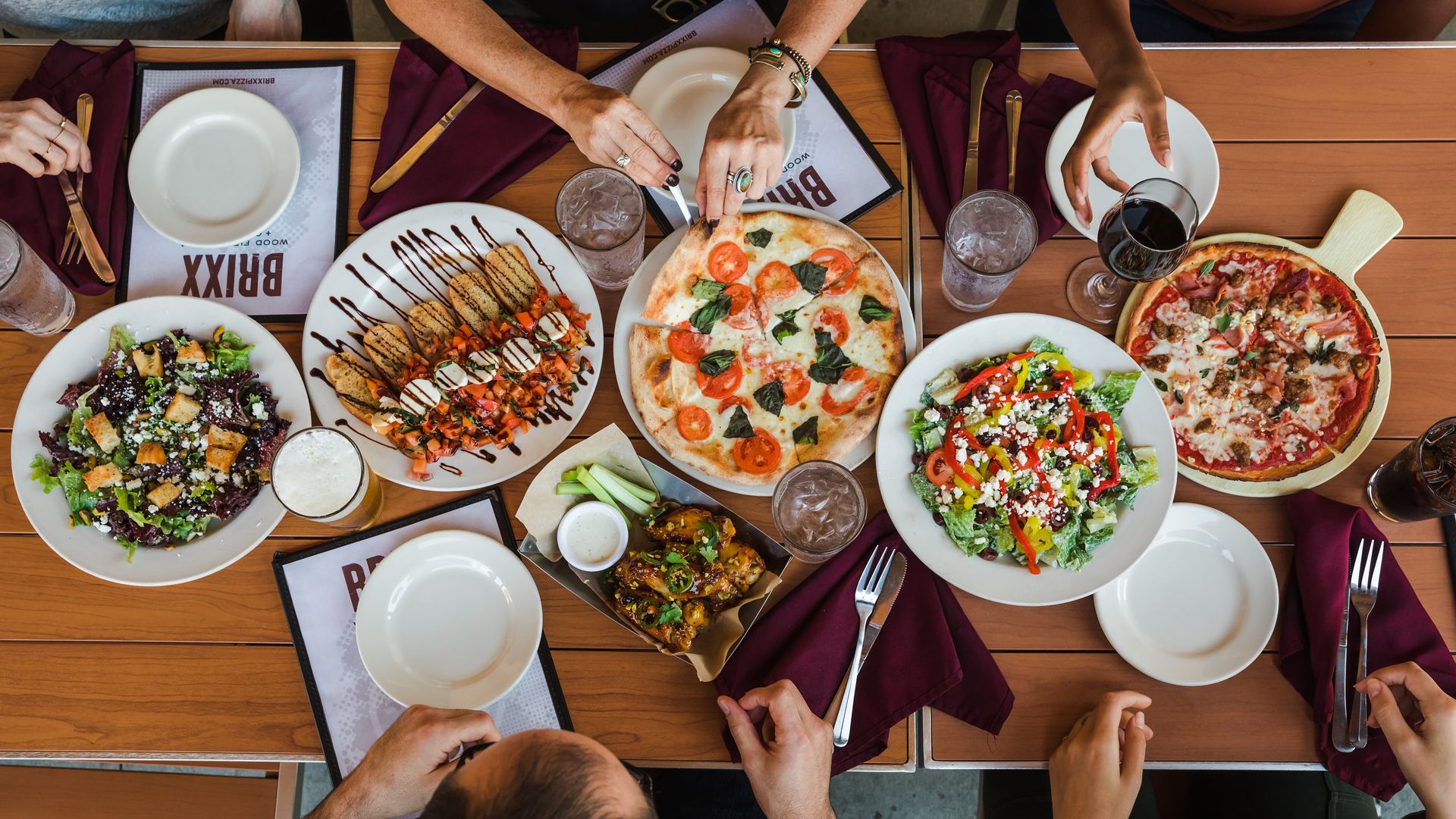 A restaurant table with plates of pizza, salad, and appetizers.