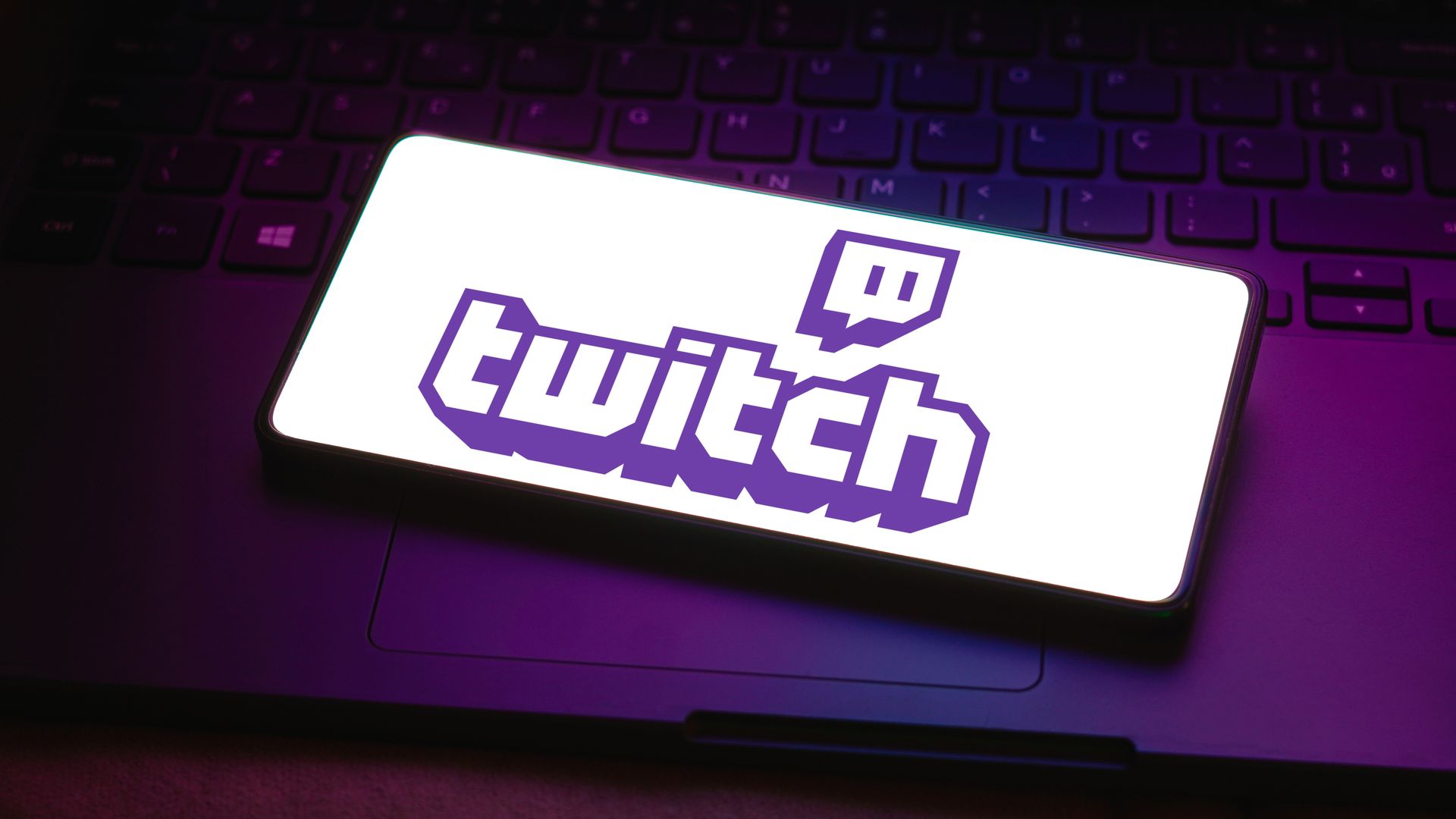 The Twitch logo on a smartphone place on a laptop. 