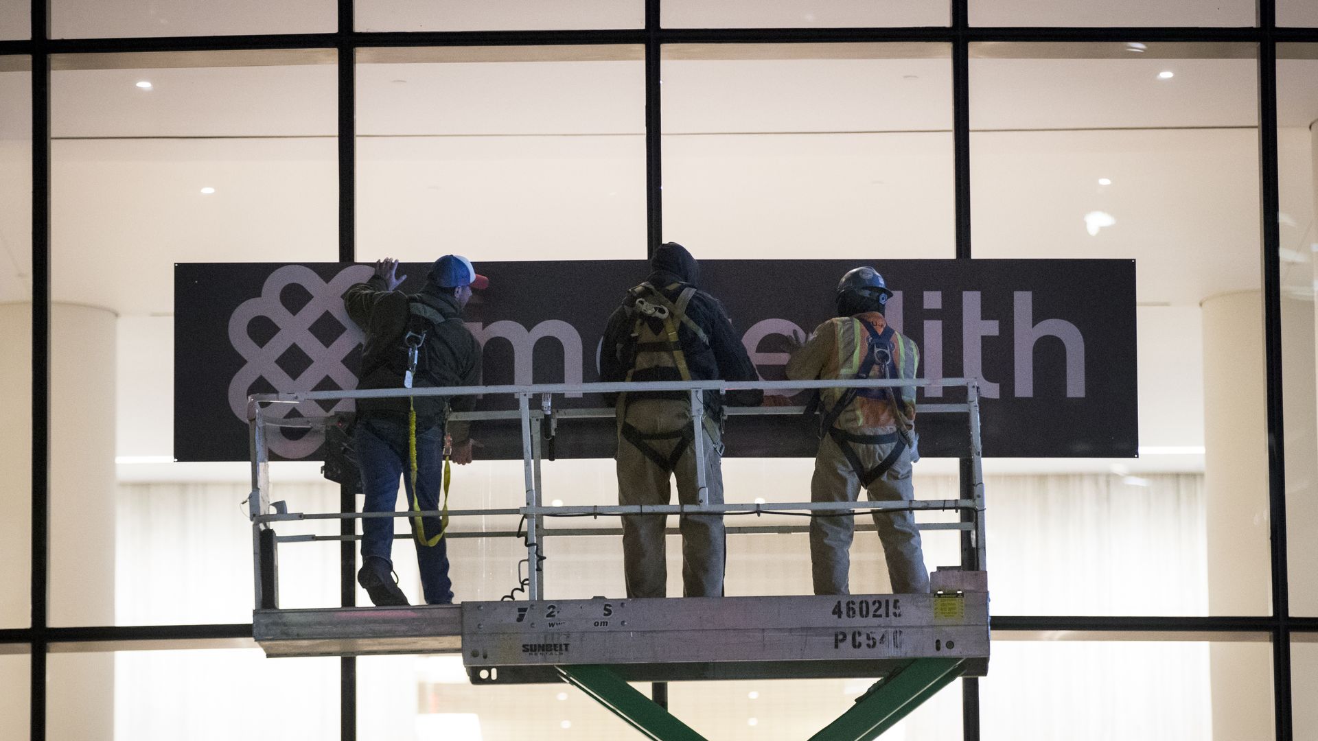Meredith workers replace the old Time Inc. logo.
