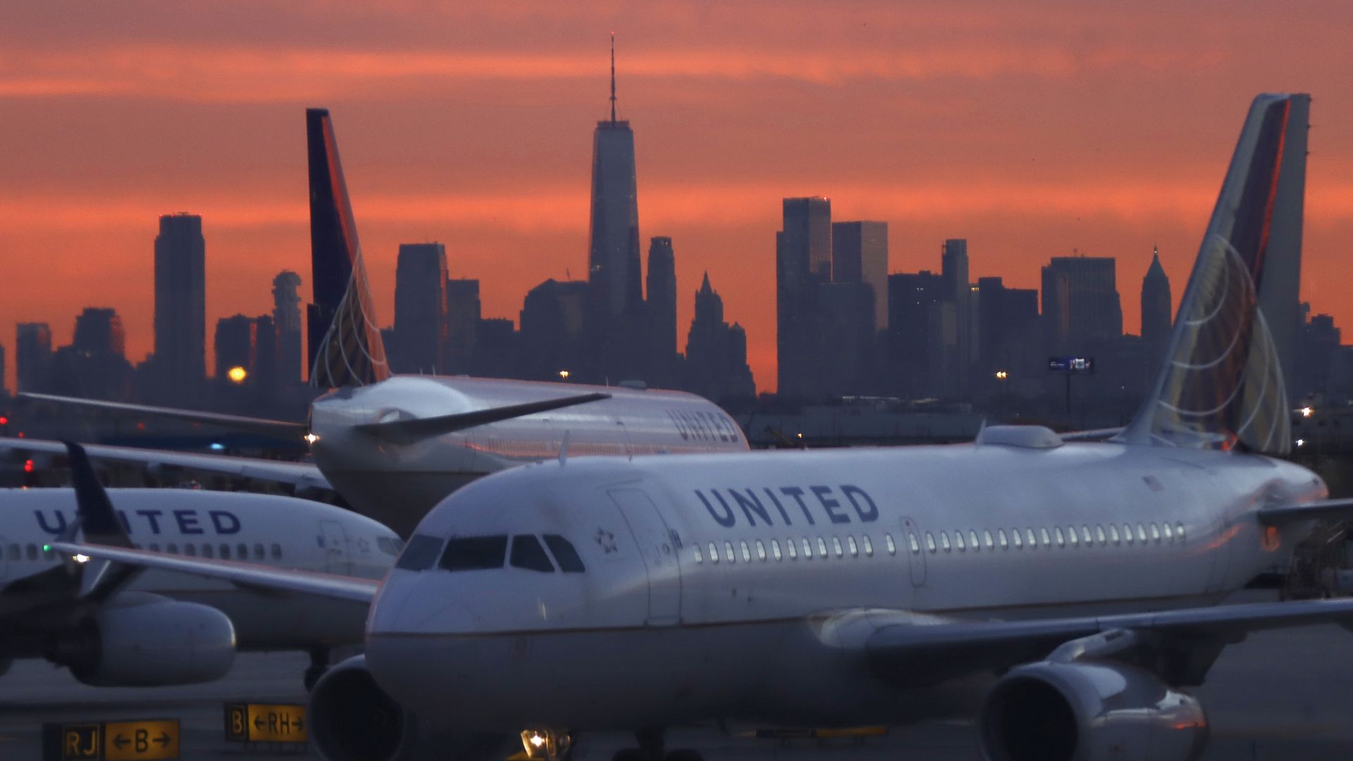  A United Airlines airplane at Newark Liberty International Airport as the sun rises behind the skyline of lower Manhattan and One World Trade Center in New York City on December 13, 2021