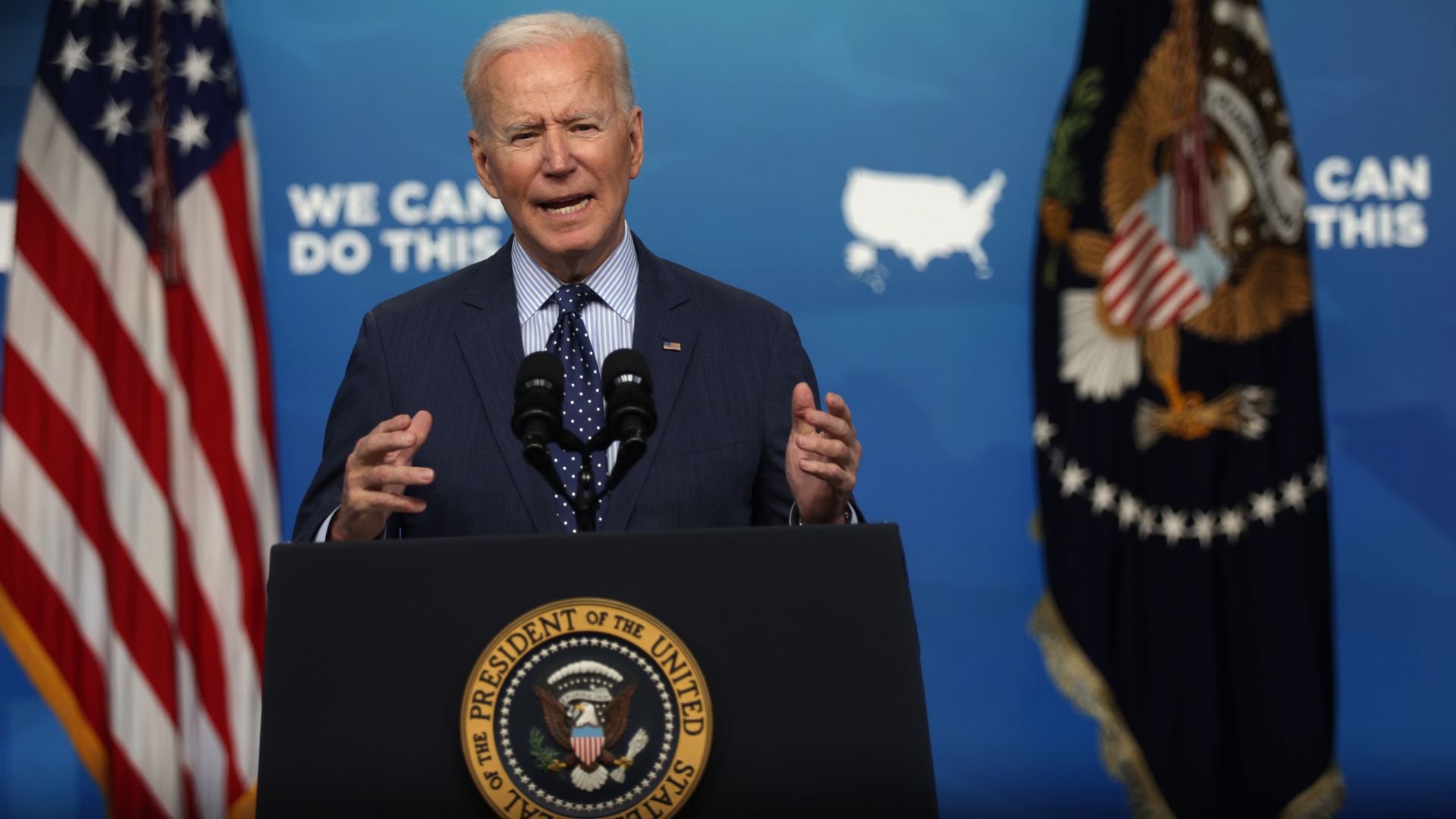 Biden stands behind a podium next to an American flag