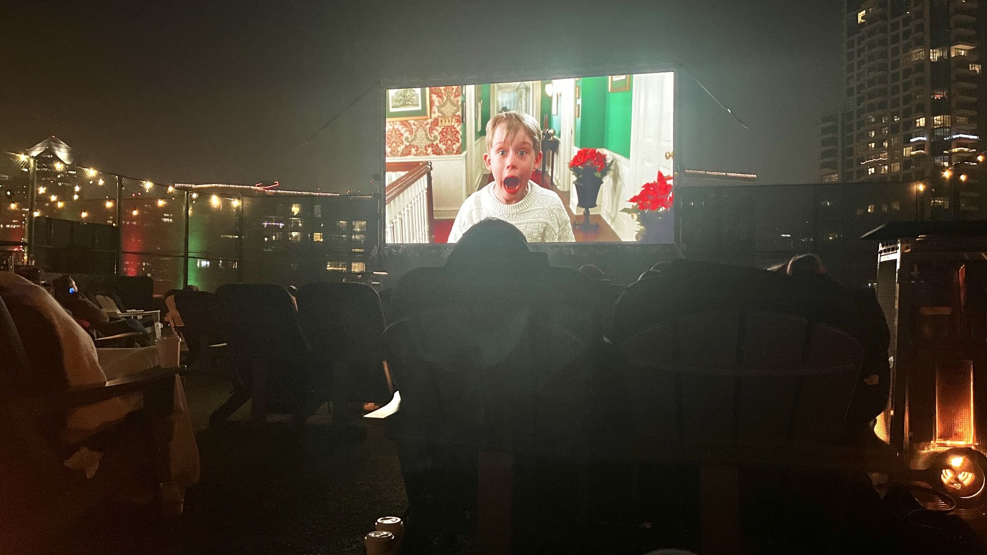 Kevin from Home Alone screams in a scene that's playing on a big screen at a rooftop cinemas at night,