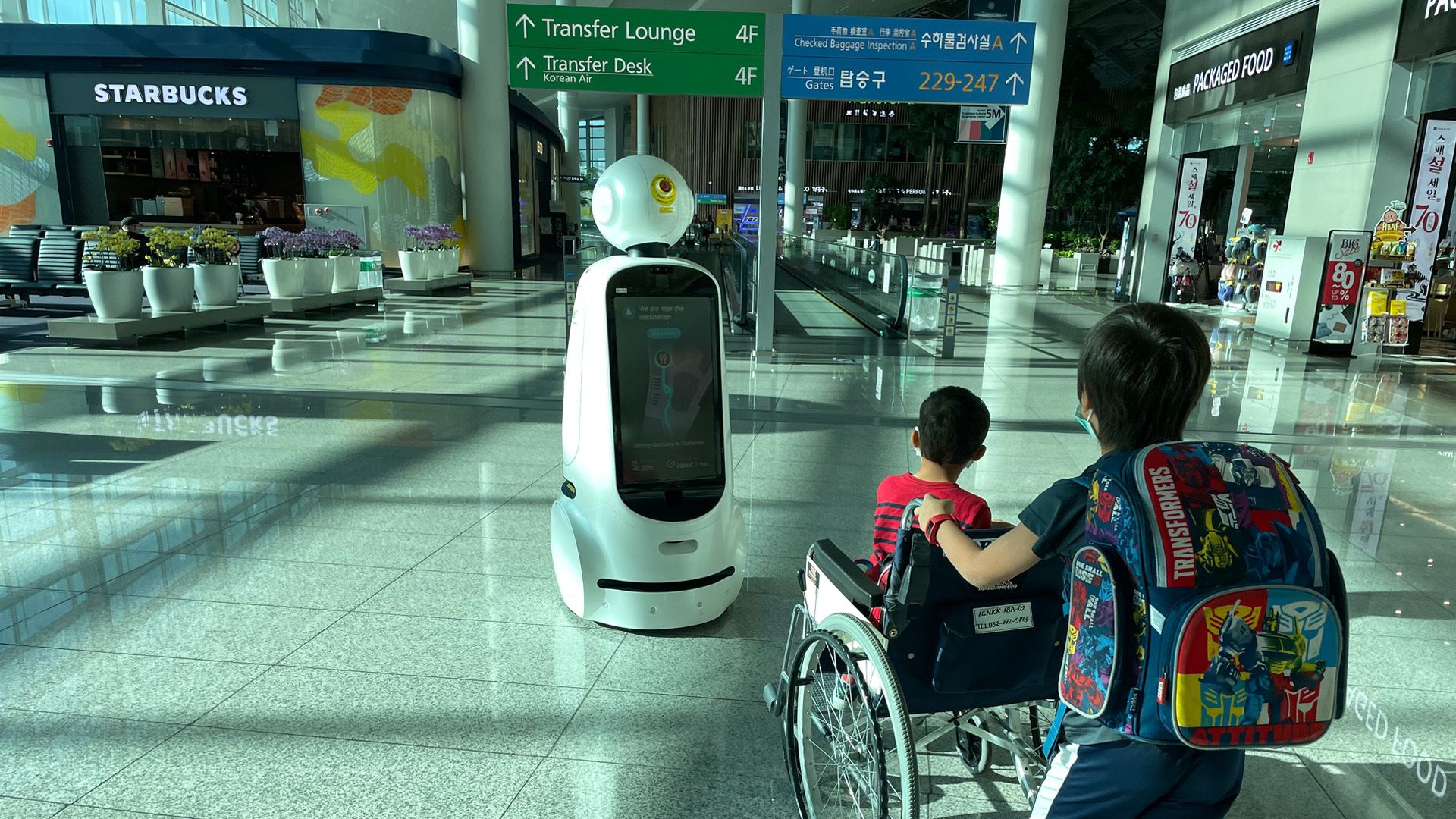 A robot called AiRSTAR leads two passengers through Incheon Airport in Seoul.