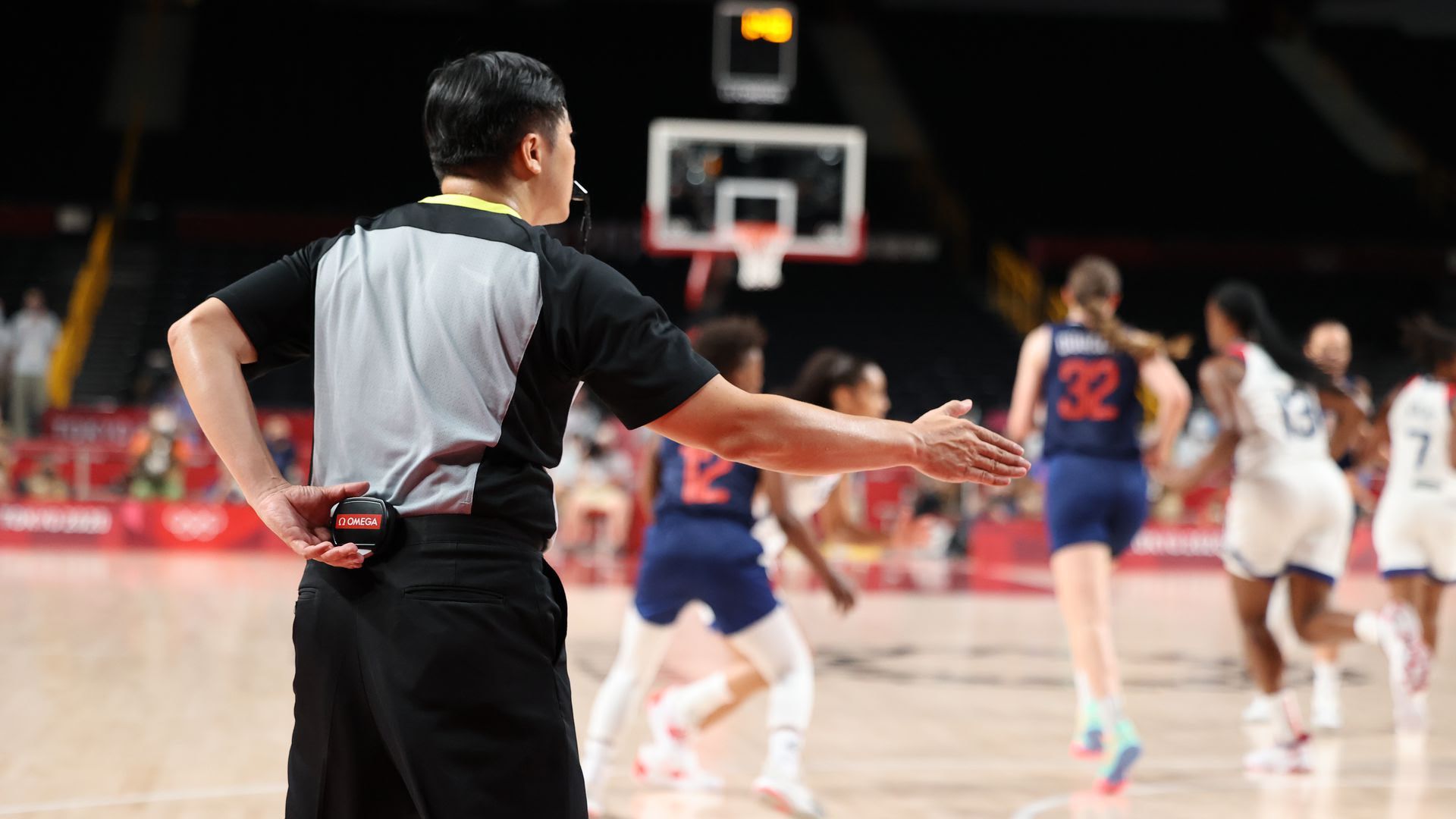 Photo of a referee at women's basketball with Omega timing device behind his back