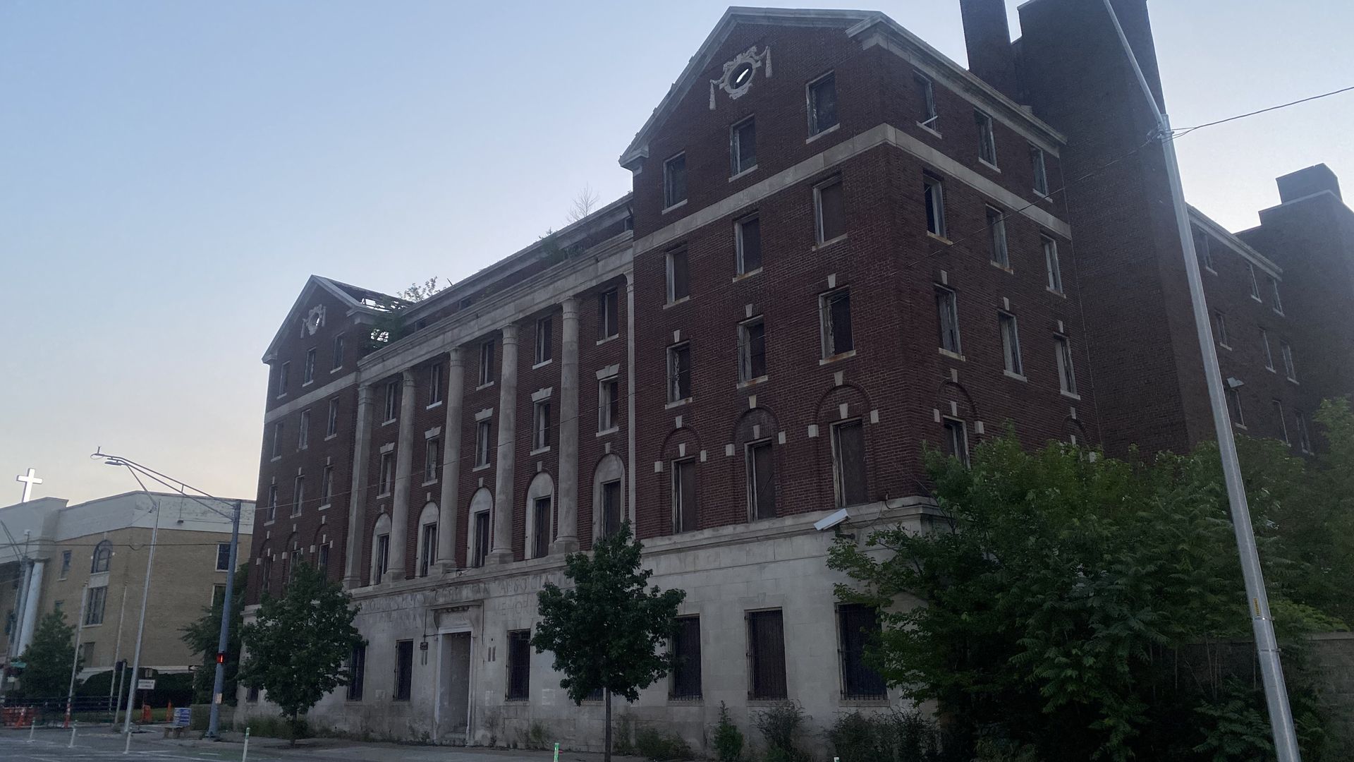 A large brick building with columns and intricate details that's vacant.