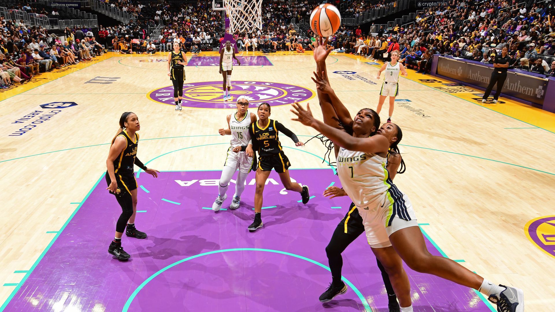 Basketball players gather around a hoop