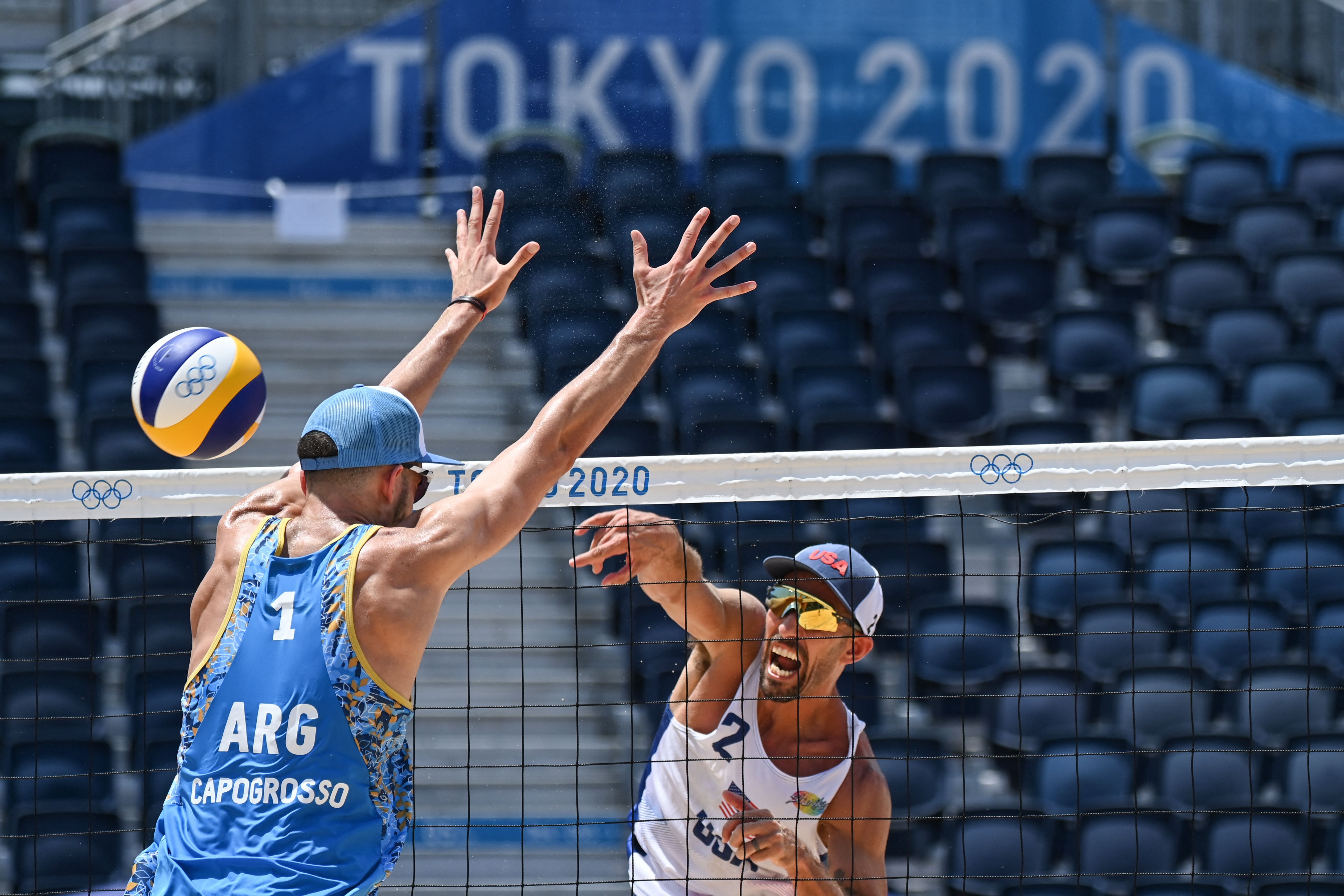Argentina's Nicolas Capogrosso (L) blocks a shot by USA's Nicholas Lucena in their men's beach volleyball match between the USA and Argentina in Tokyo on July 29
