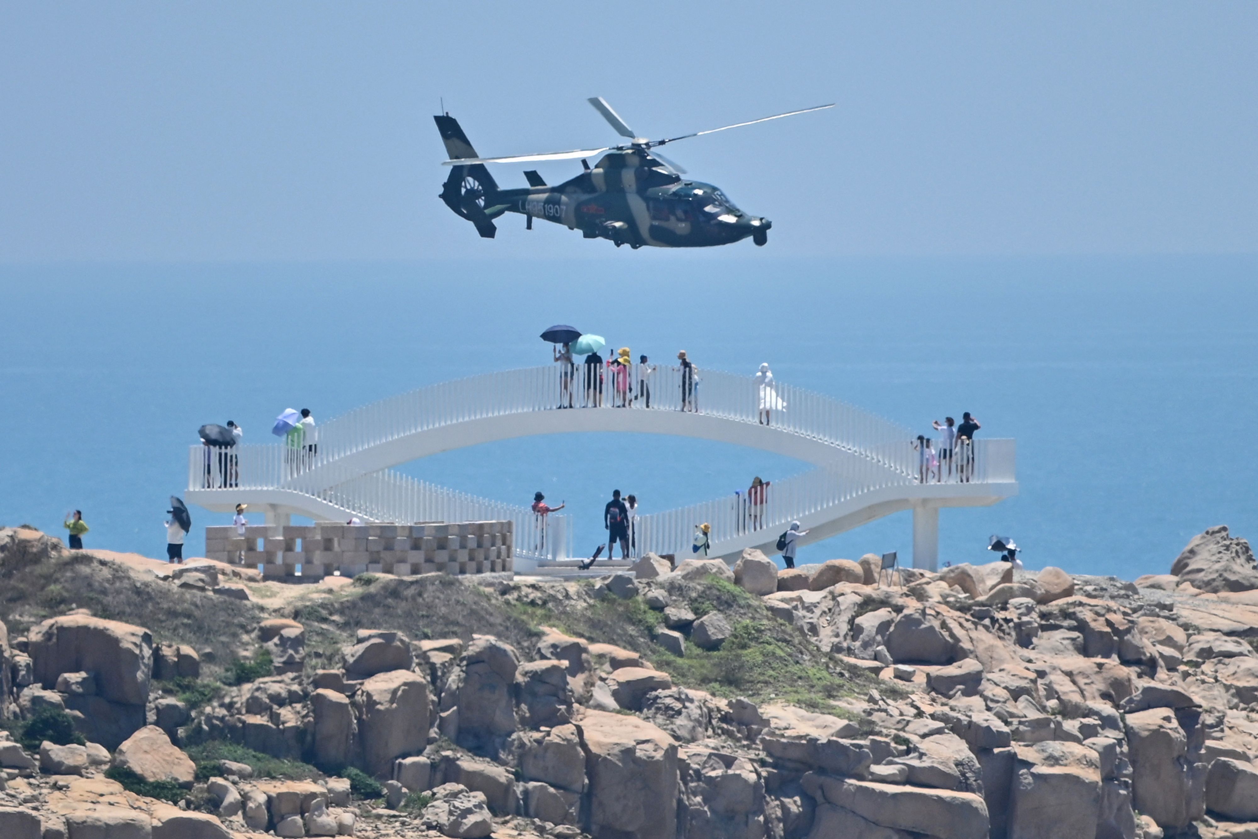  Tourists look on as a Chinese military helicopter flies past Pingtan island, one of mainland China's closest point from Taiwan, in Fujian province on August 4.