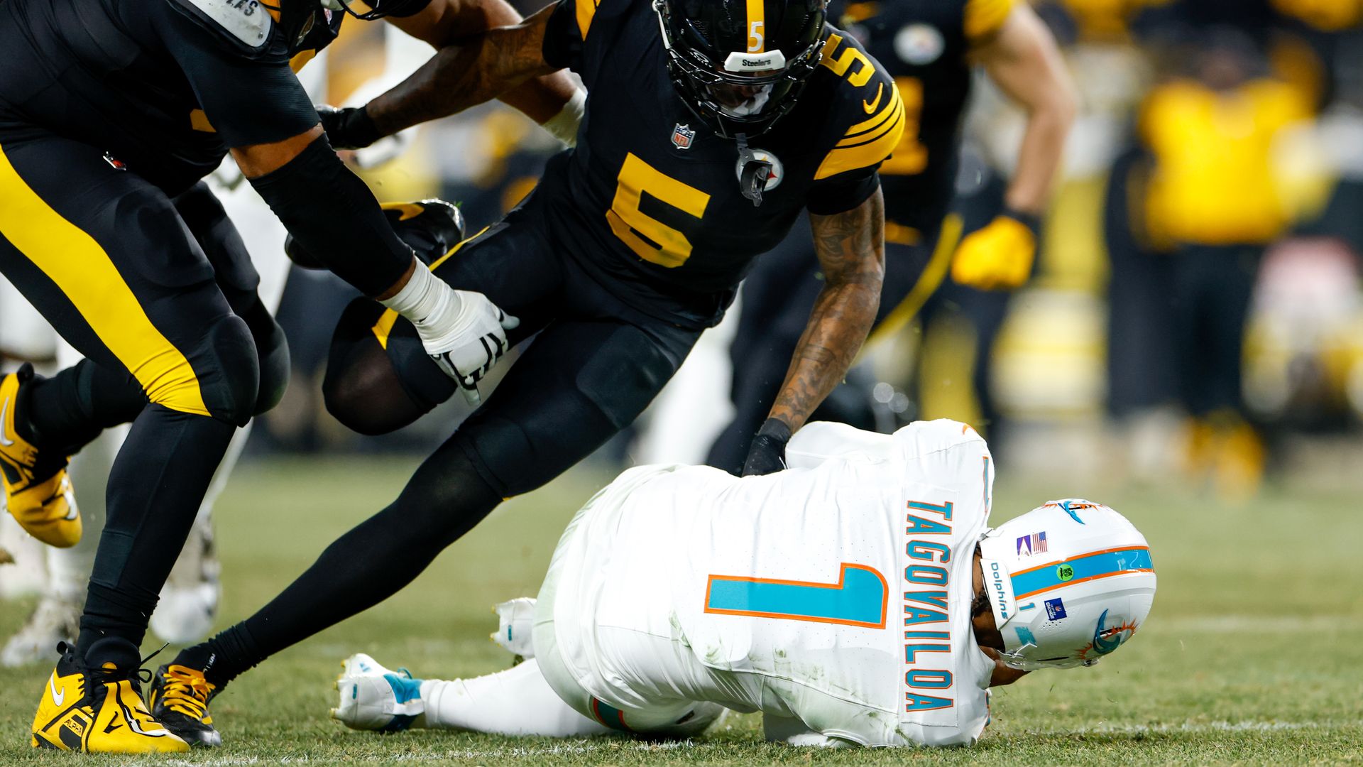 Dolphins QB Tua Tagovailoa on the ground while Steelers players above him.