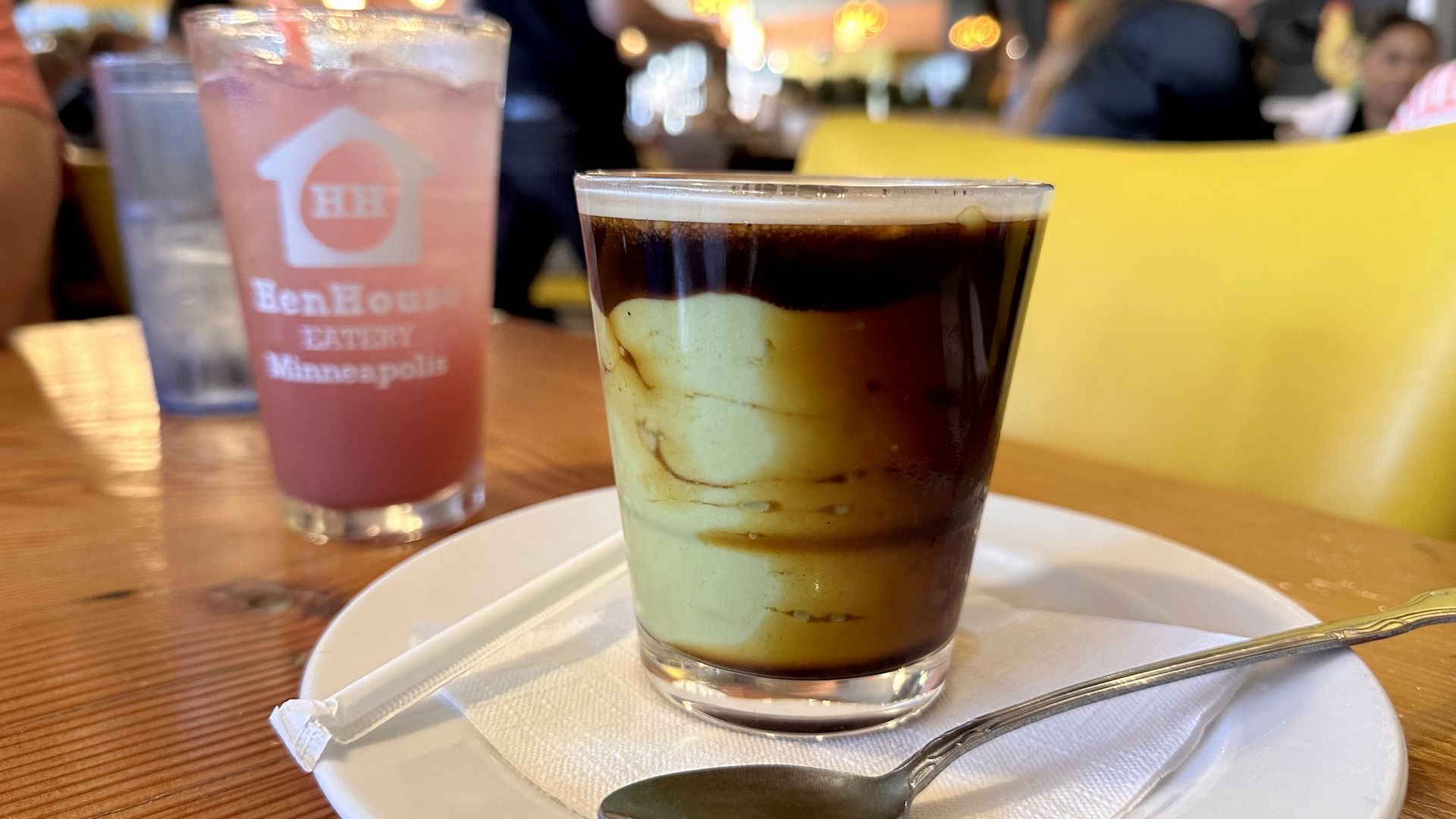 A photo of an avocado blend topped with espresso and a pink margarita in the background