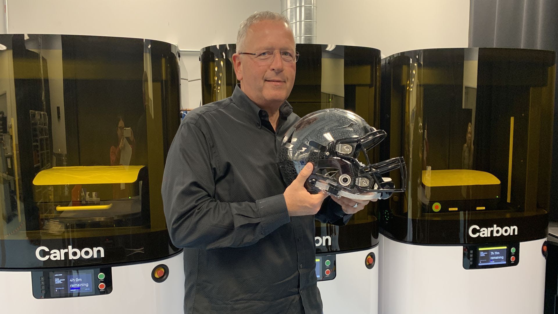 Carbon CEO Joe DeSimone holding a football helmet with 3D printed inserts using its new L1 printer. 