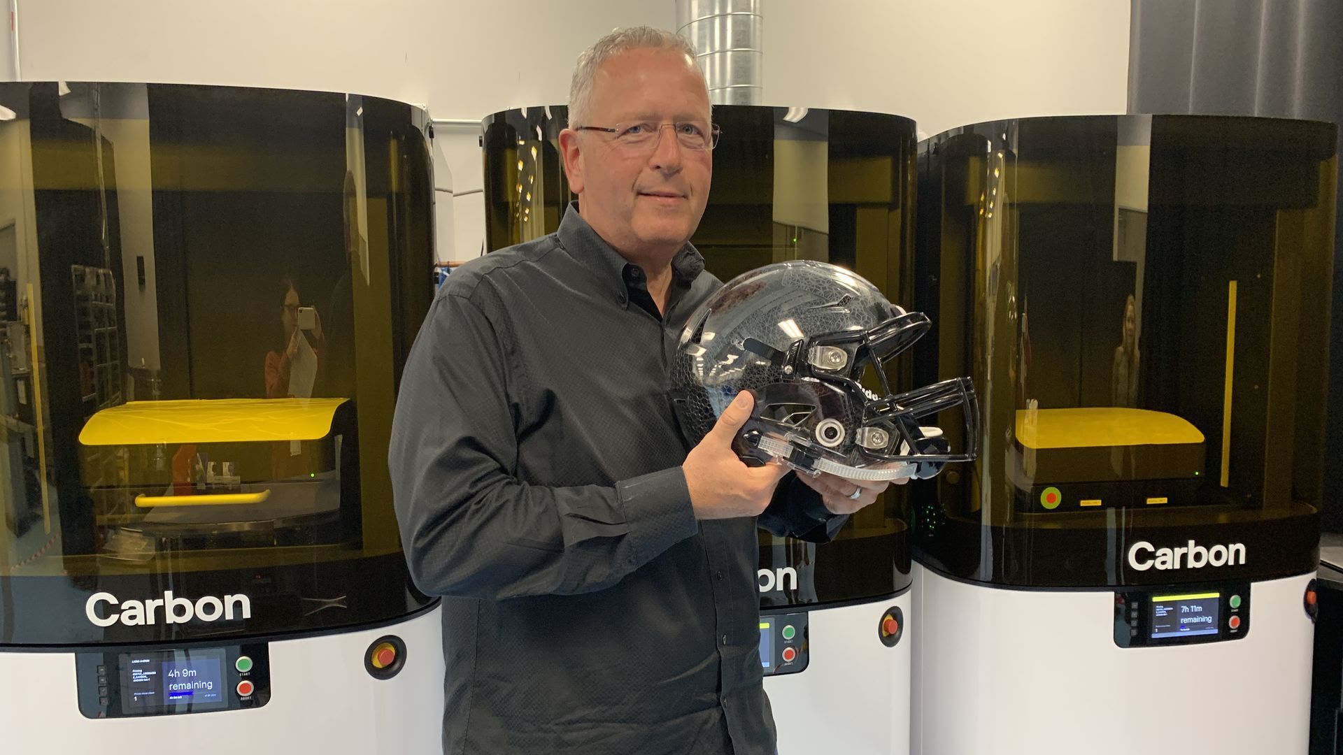 Carbon CEO Joe DeSimone holding a football helmet with 3D printed inserts using its new L1 printer.