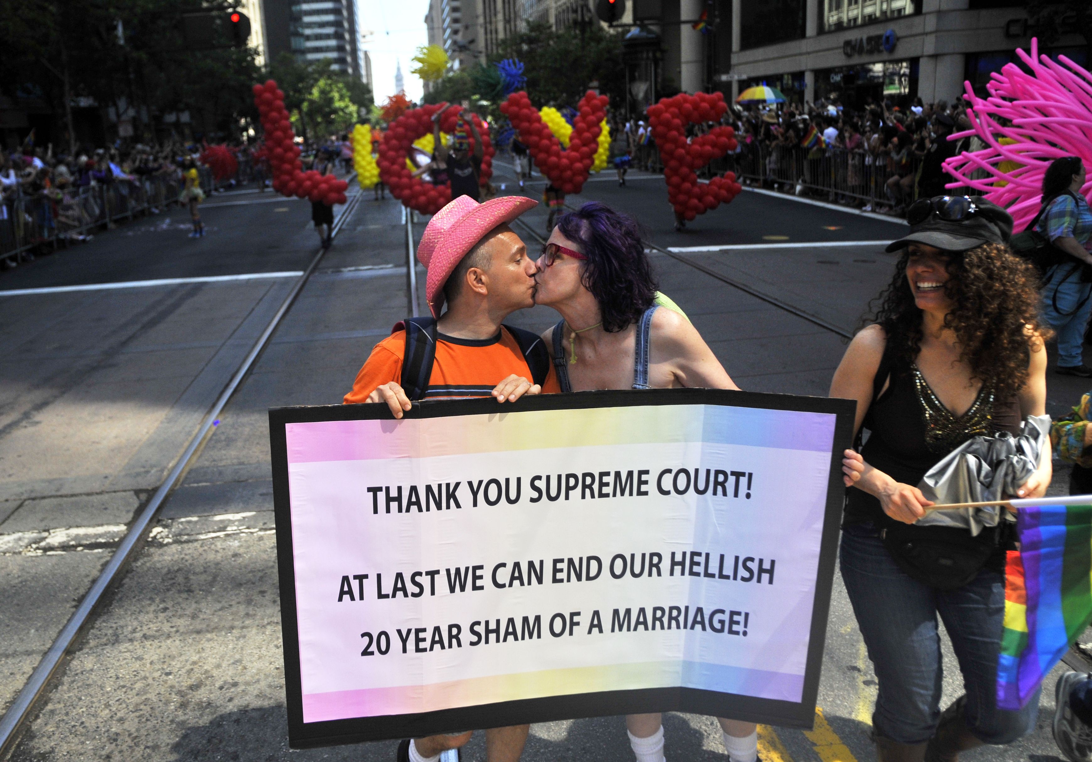 Photo of a man and a woman kissing while holding a sign that says "Thank you Supreme Court! At last we can end our hellish 20 year sham of a marriage!"
