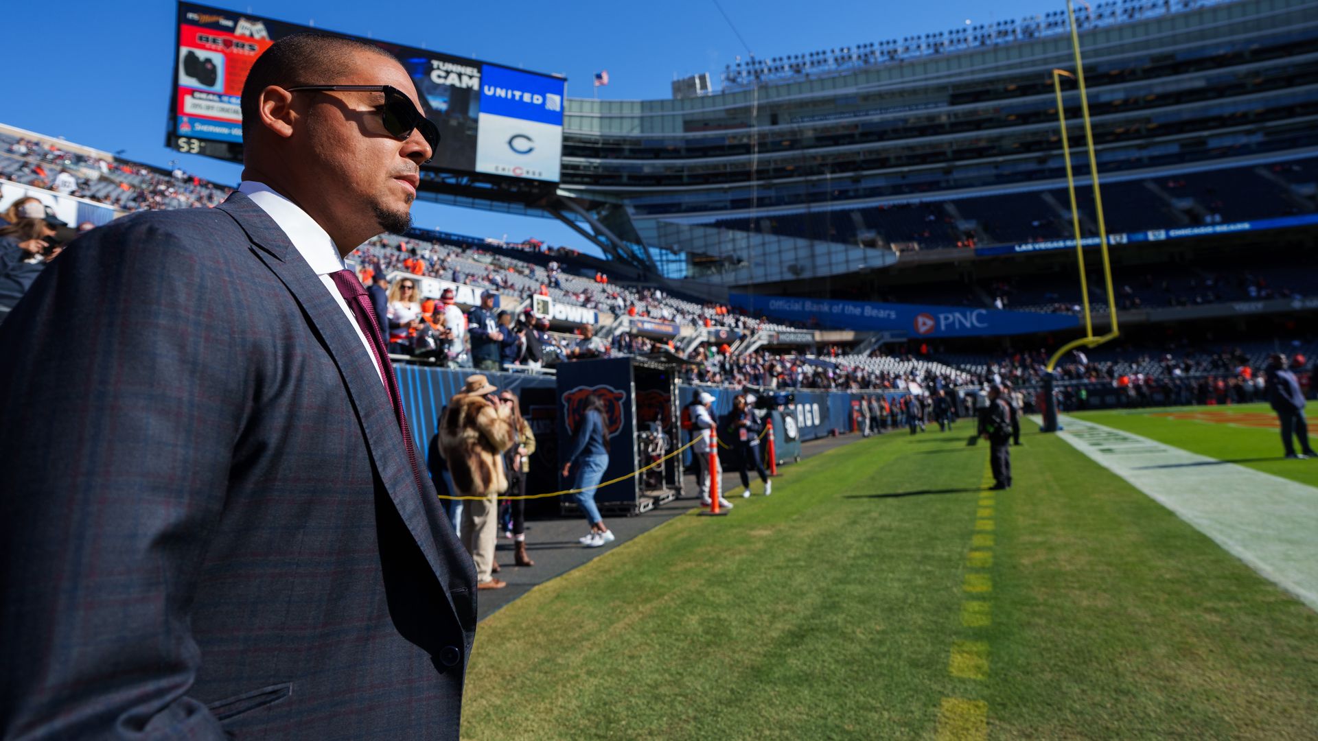 guy in suit standing on football field sidelines
