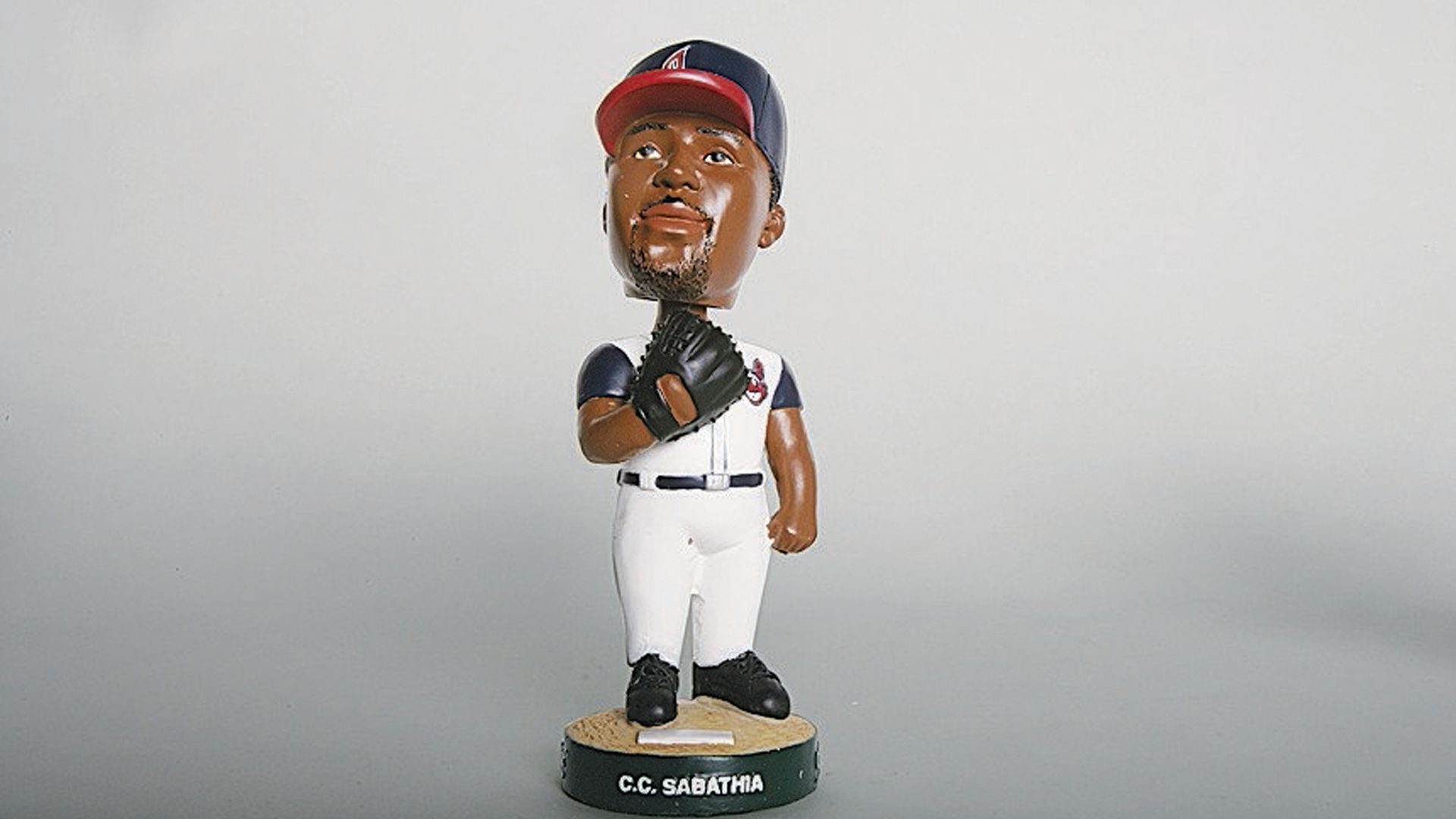 Bobblehead figurine of baseball player C.C. Sabathia in white uniform and navy cap with a glove on his left hand, standing on a base with his name on the pedestal.