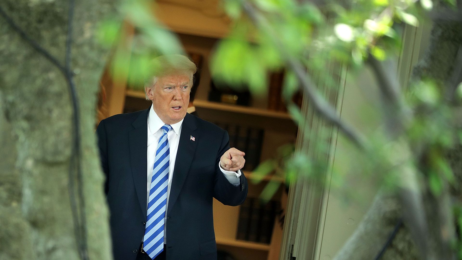 President Trump in a dark suit, white shirt and light blue striped tie pointing his finger