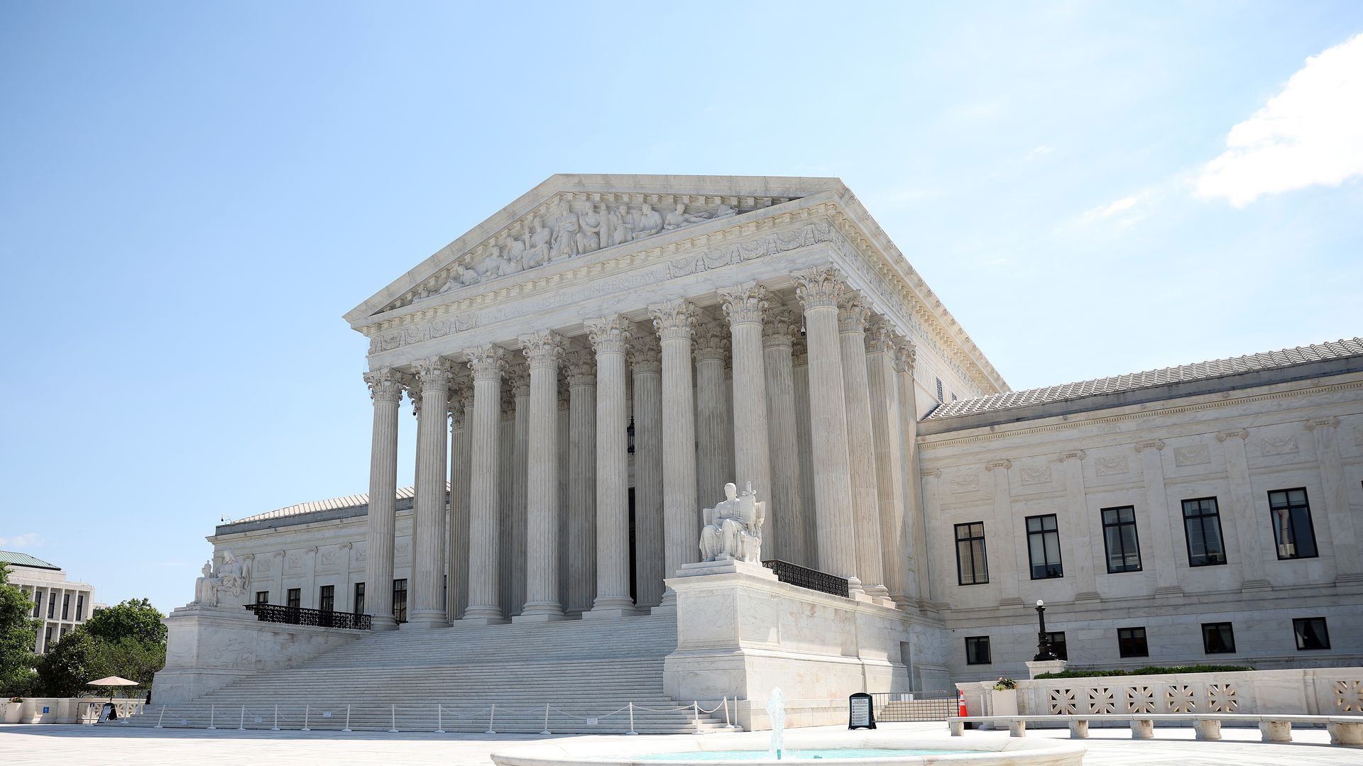 An exterior view of the front of the United States Supreme Court, a classical-style building with steps leading up to a front entrance with eight columns. 