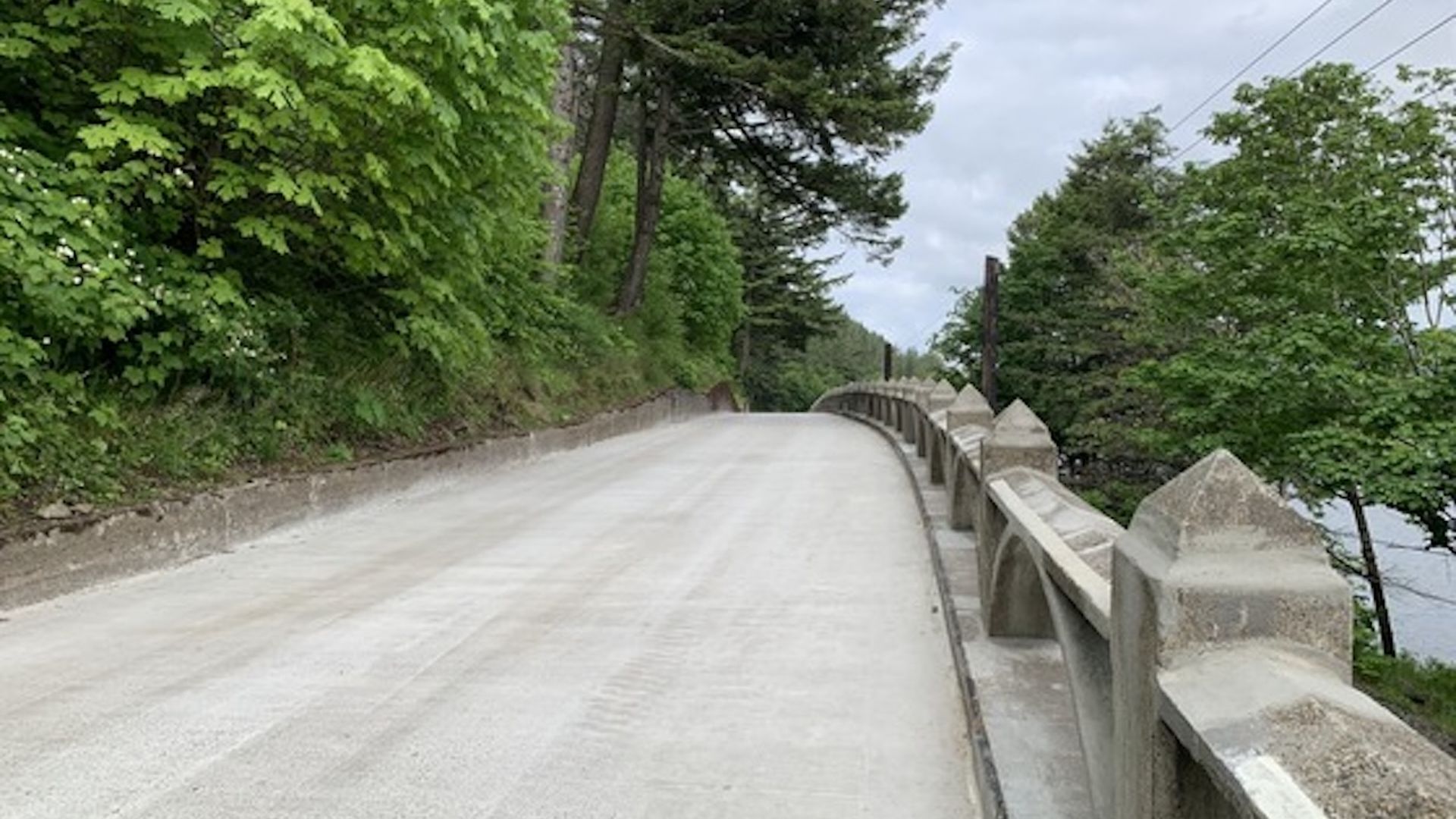 A historic road runs through a forest with art deco decorations along the side.