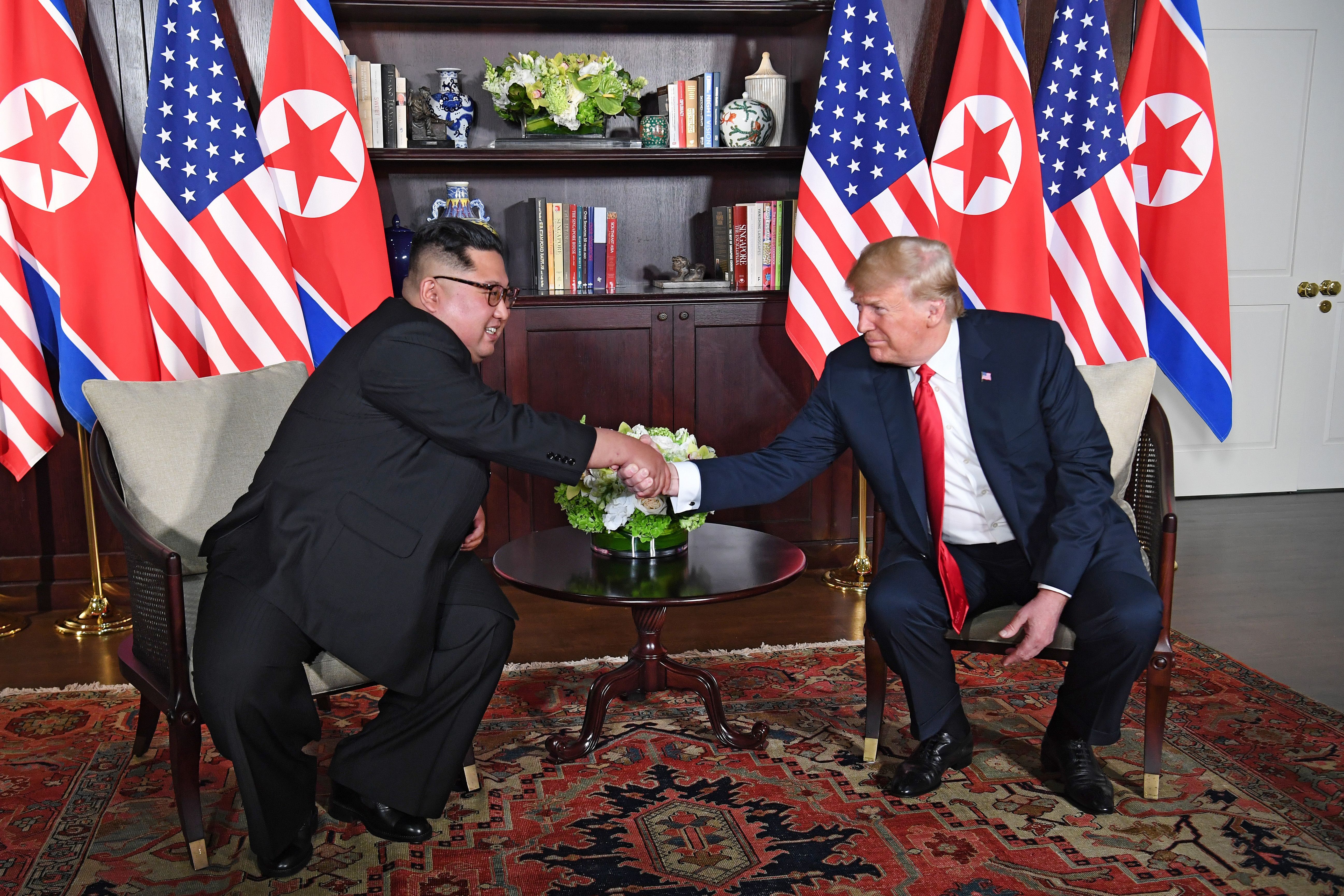 President Trump and Kim Jong-un shaking hands while seated in chairs