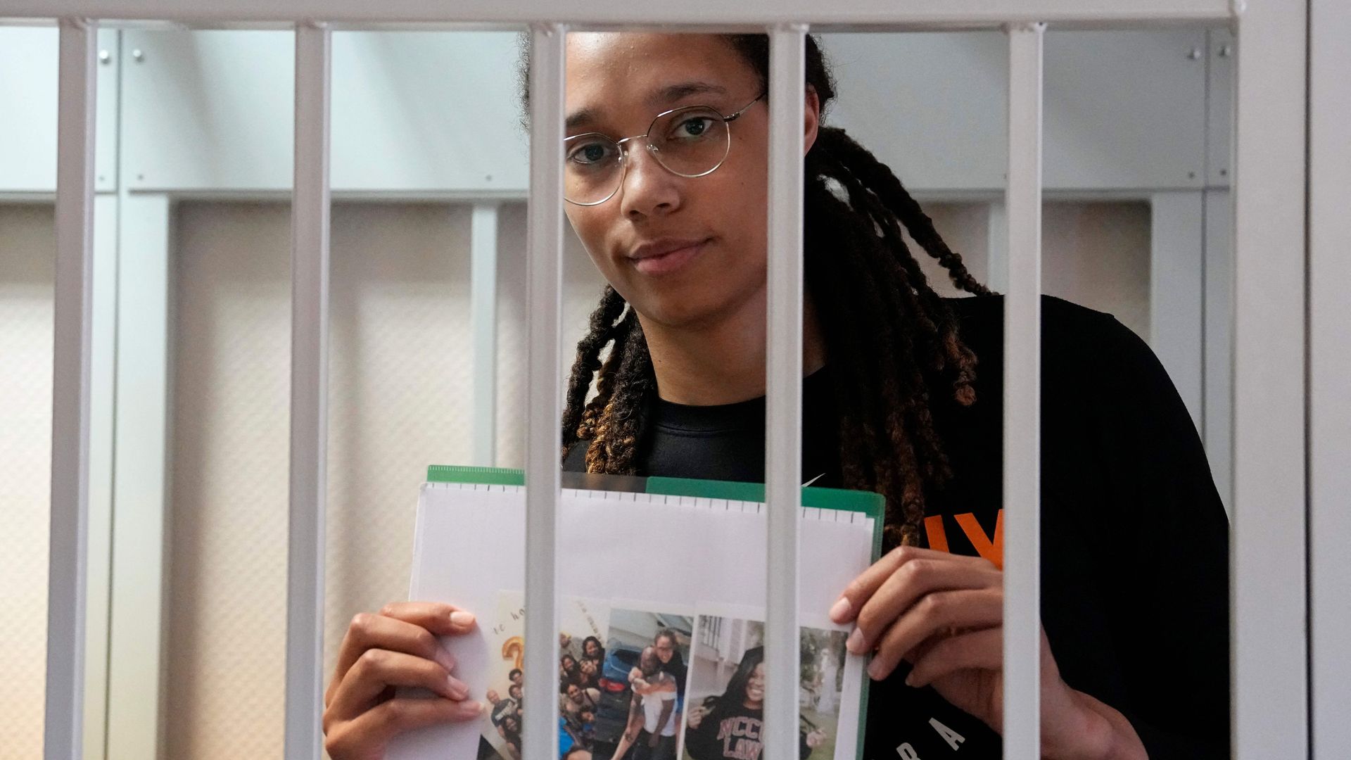 WNBA basketball superstar Brittney Griner holds photographs standing inside a defendants' cage before a hearing at the Khimki Court, outside Moscow on July 27, 2022