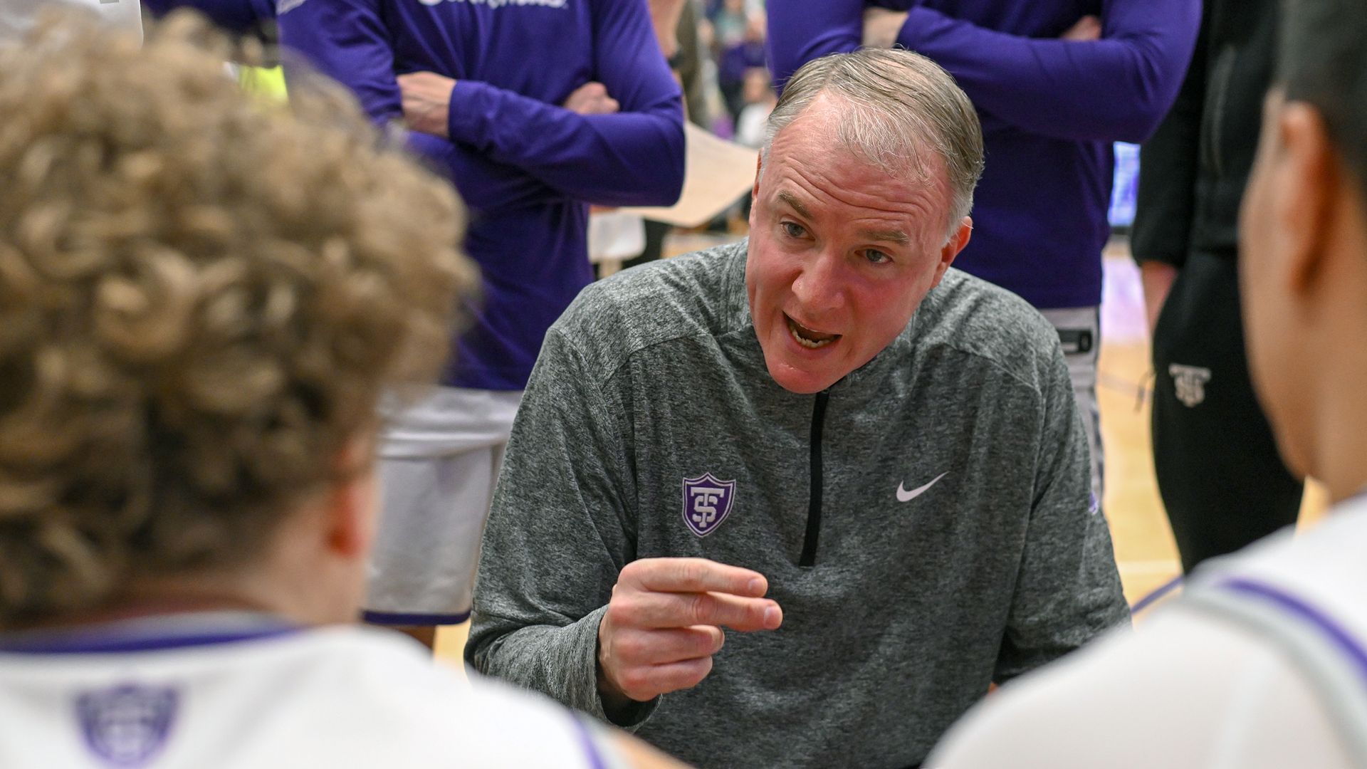 A photo John Tauer talking to two players