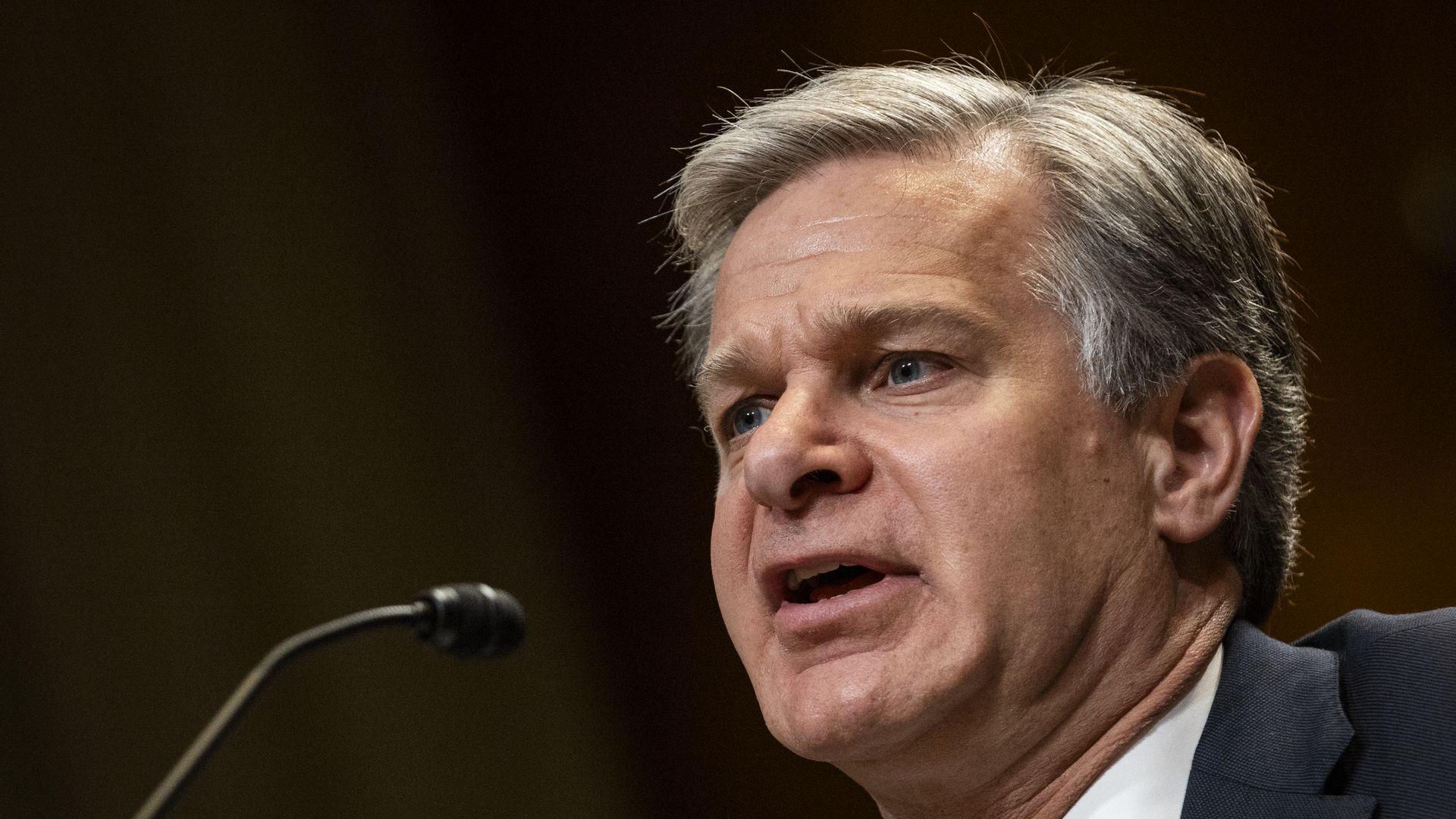 Then-FBI Director Christopher Wray, with gray hair and wearing a navy jacket with a US flag pin and a white shirt, testifies during a Senate Appropriations Subcommittee hearing in Washington, D.C.,
