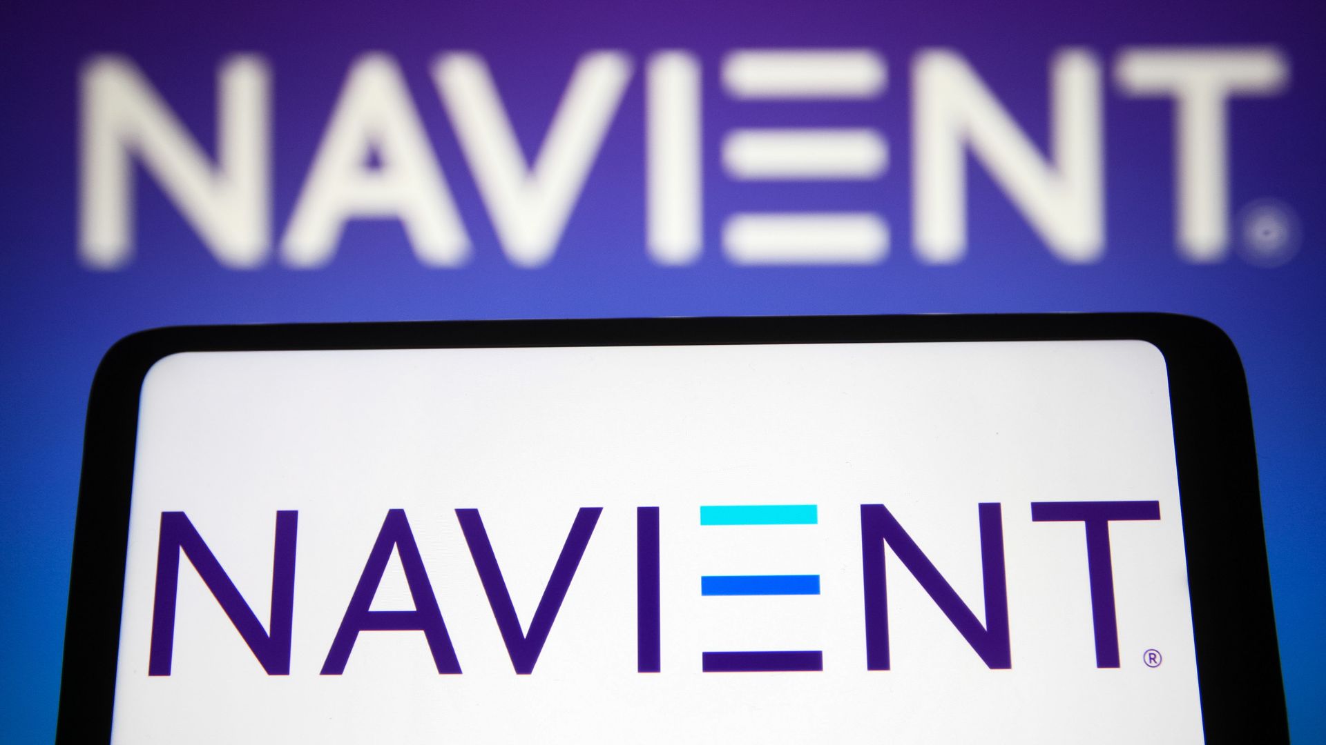 In this photo illustration, the Navient Corporation logo is seen displayed on a smartphone and in the background.