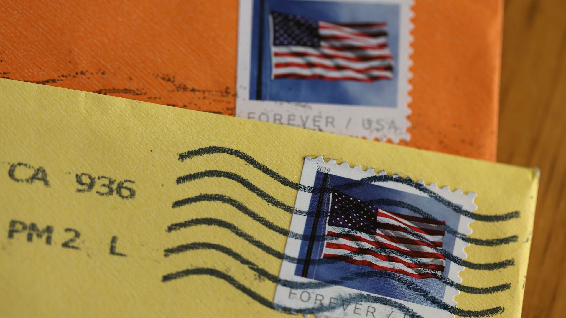 Postage stamps on colored envelopes with postmark through them