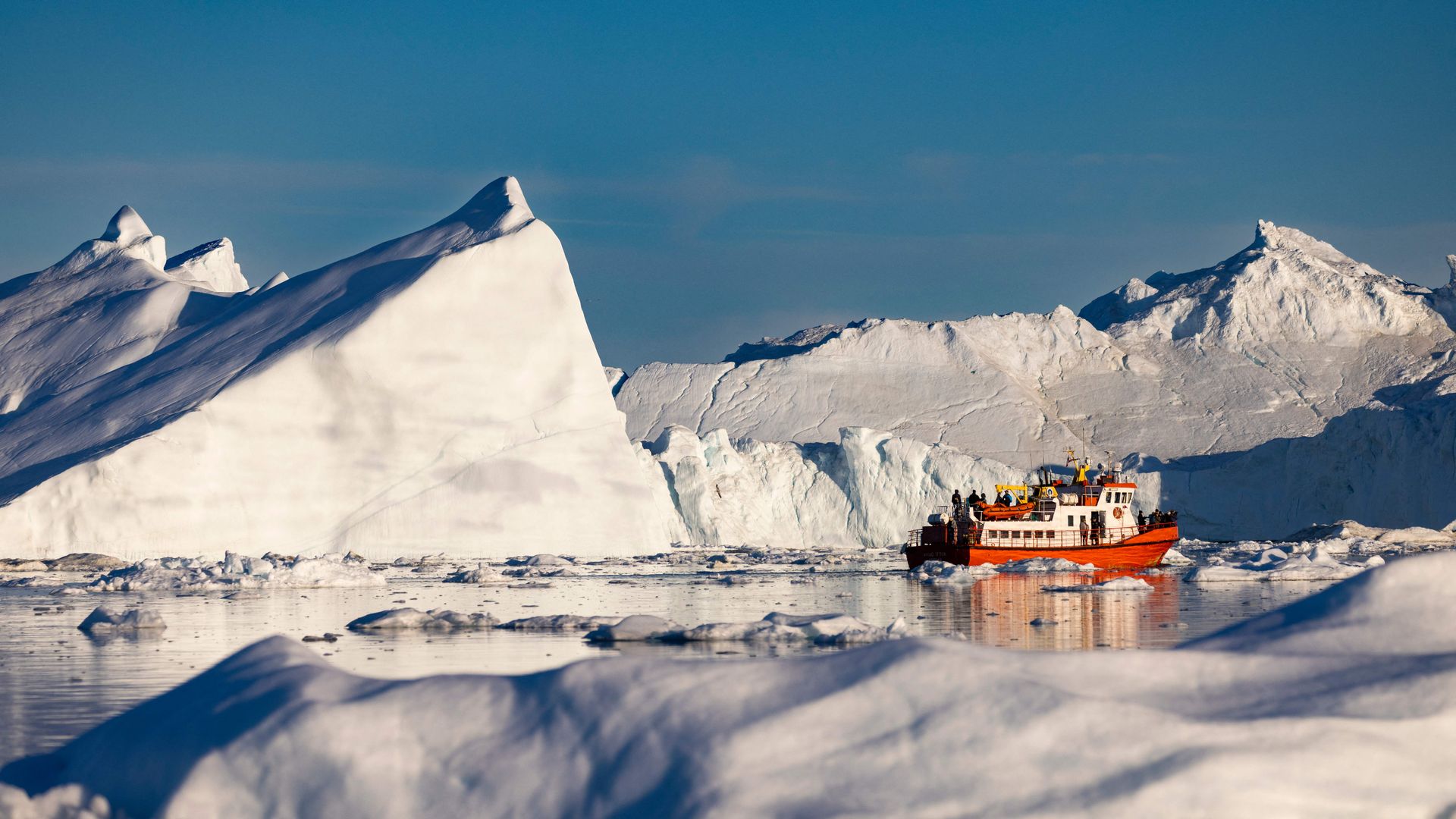 Picture of a boat carrying tourists moves among icebergs floating in Disko Bay, Ilulissat, western Greenland.