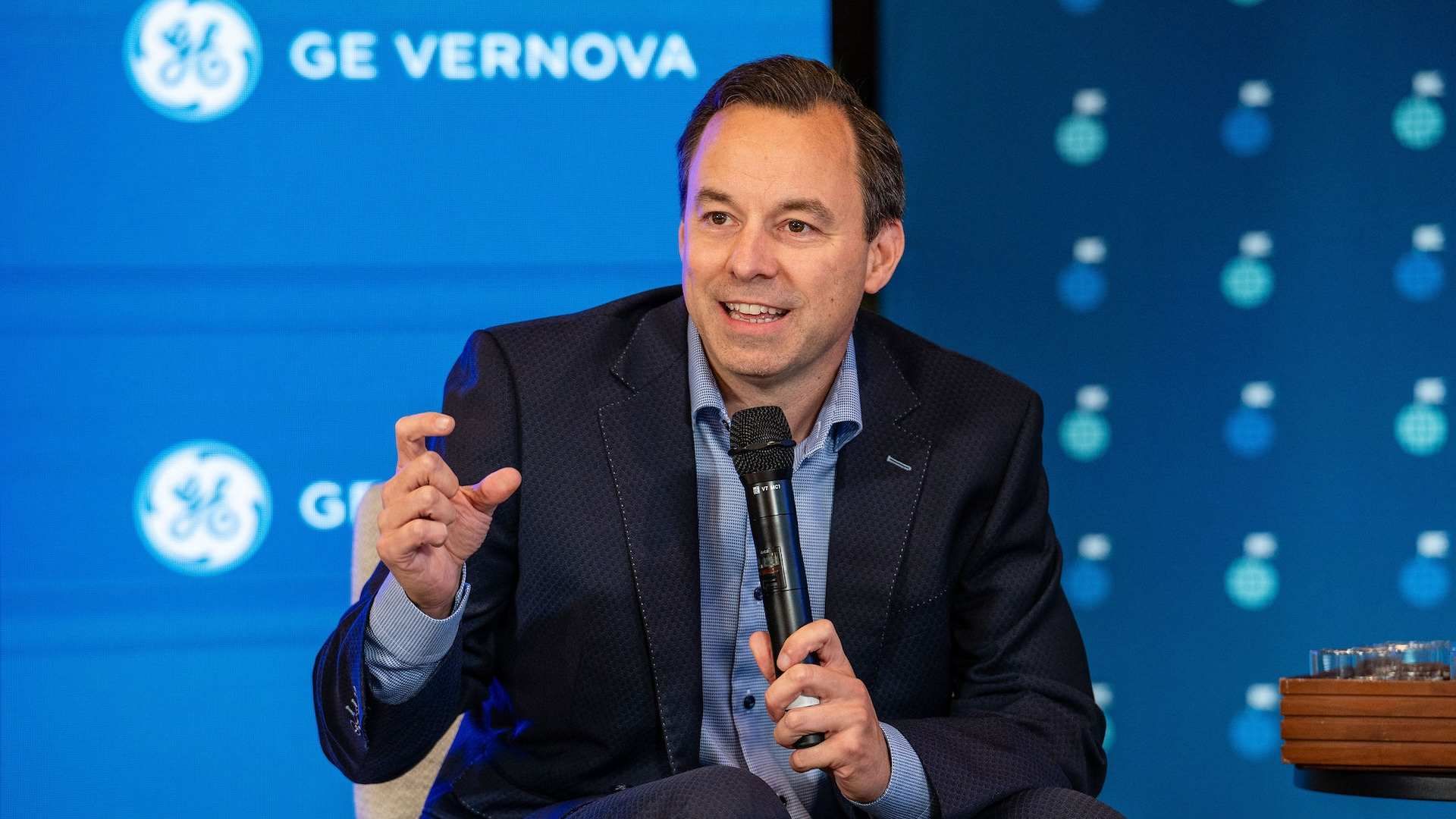 A man wearing a suit holding a microphone. 