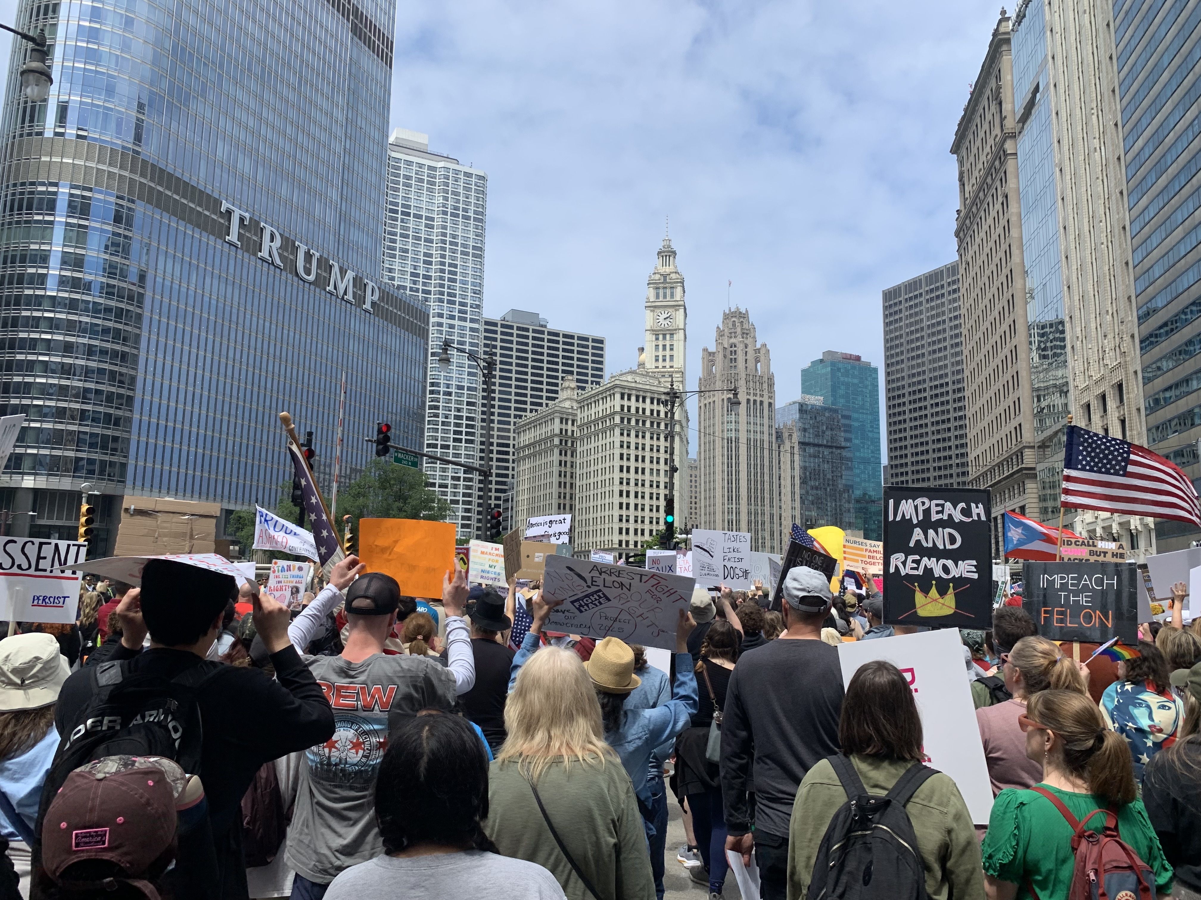 Protesters fill up a plaza with signs and march on a street. 