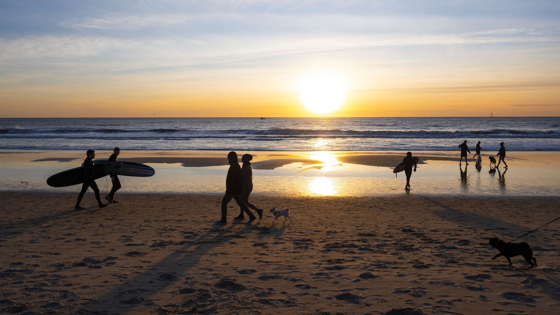 Photo of people walking on the beach as the sun sets