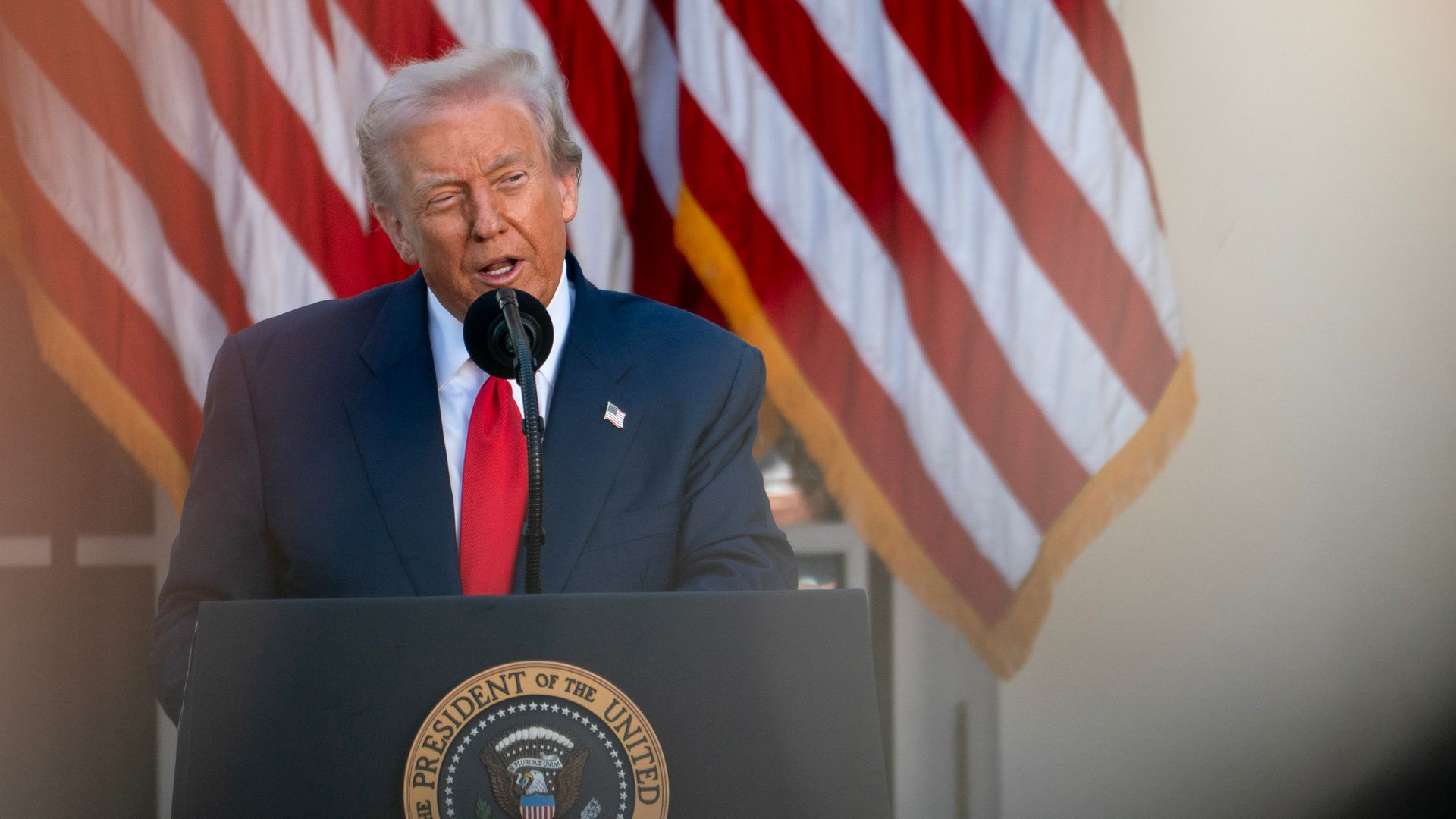 President Trump speaks behind a podium and in front of U.S. flags.