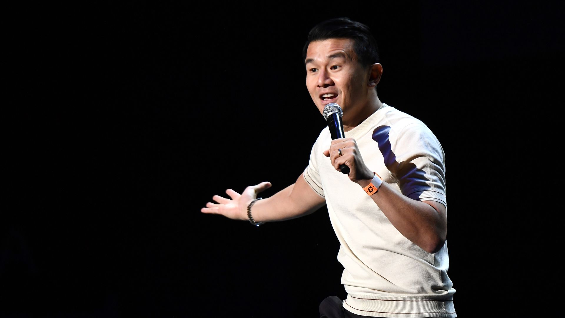 A person holding a microphone gestures.