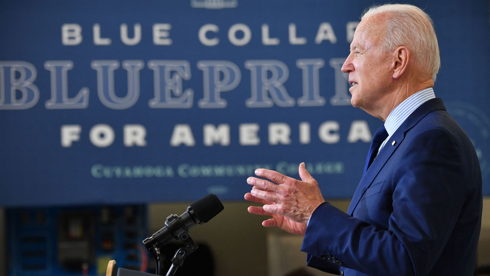 President Biden speaks in silhouette against the backdrop of a sign that says "Blue collar blueprint for America."