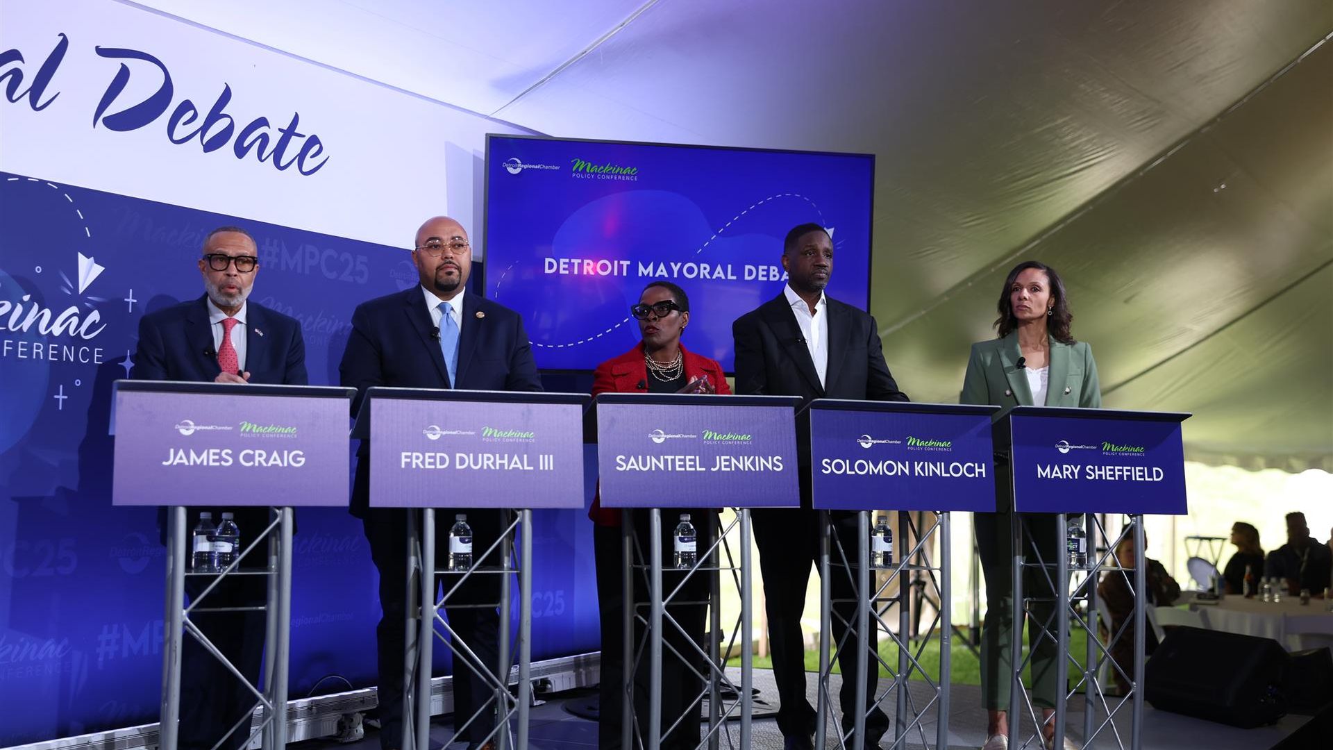 The candidates stand on stage.